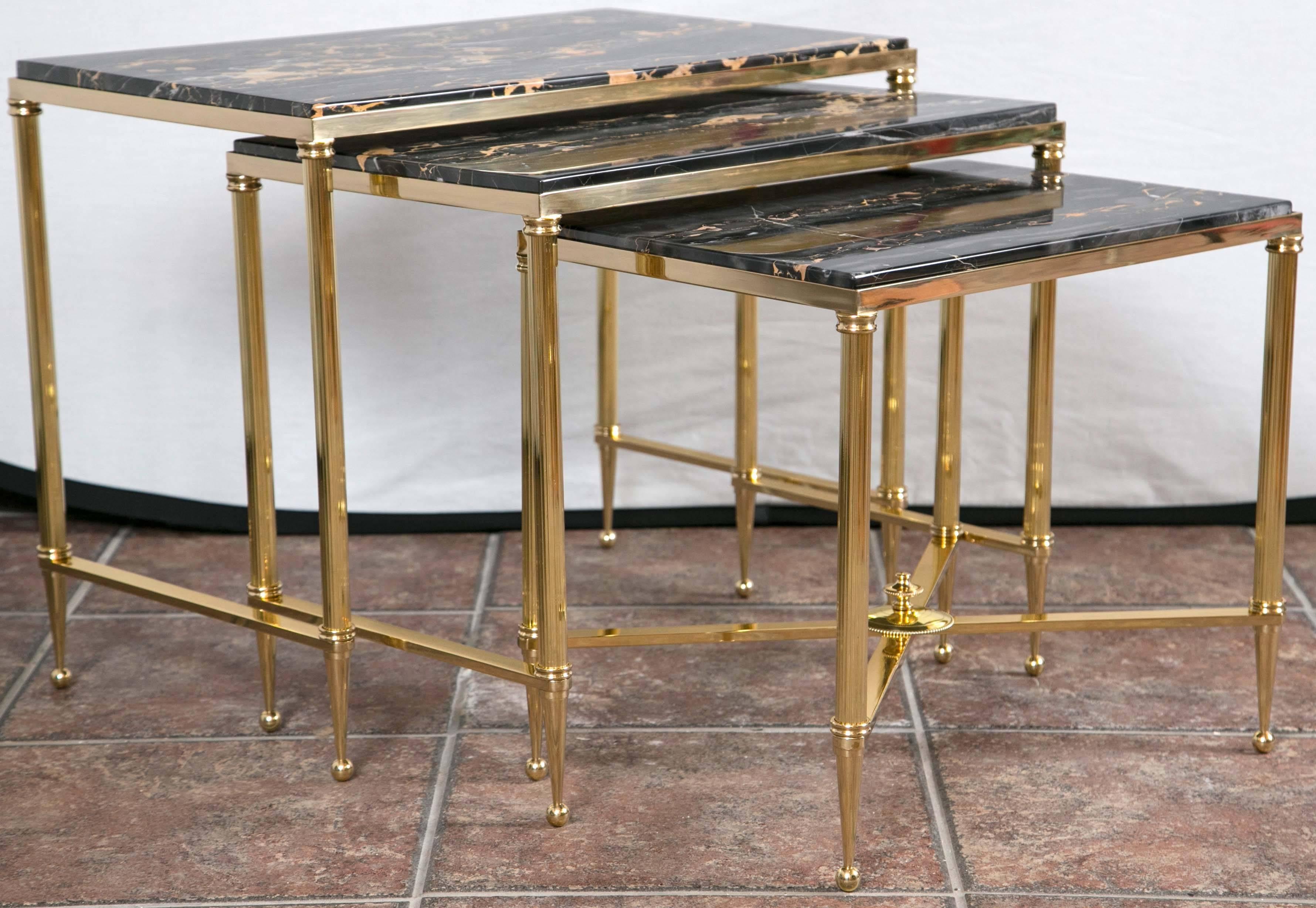 Set of three bronze Mid-Century Modern nesting tables having inset black/brown marble tops supported on reeded columns and tapered feet.