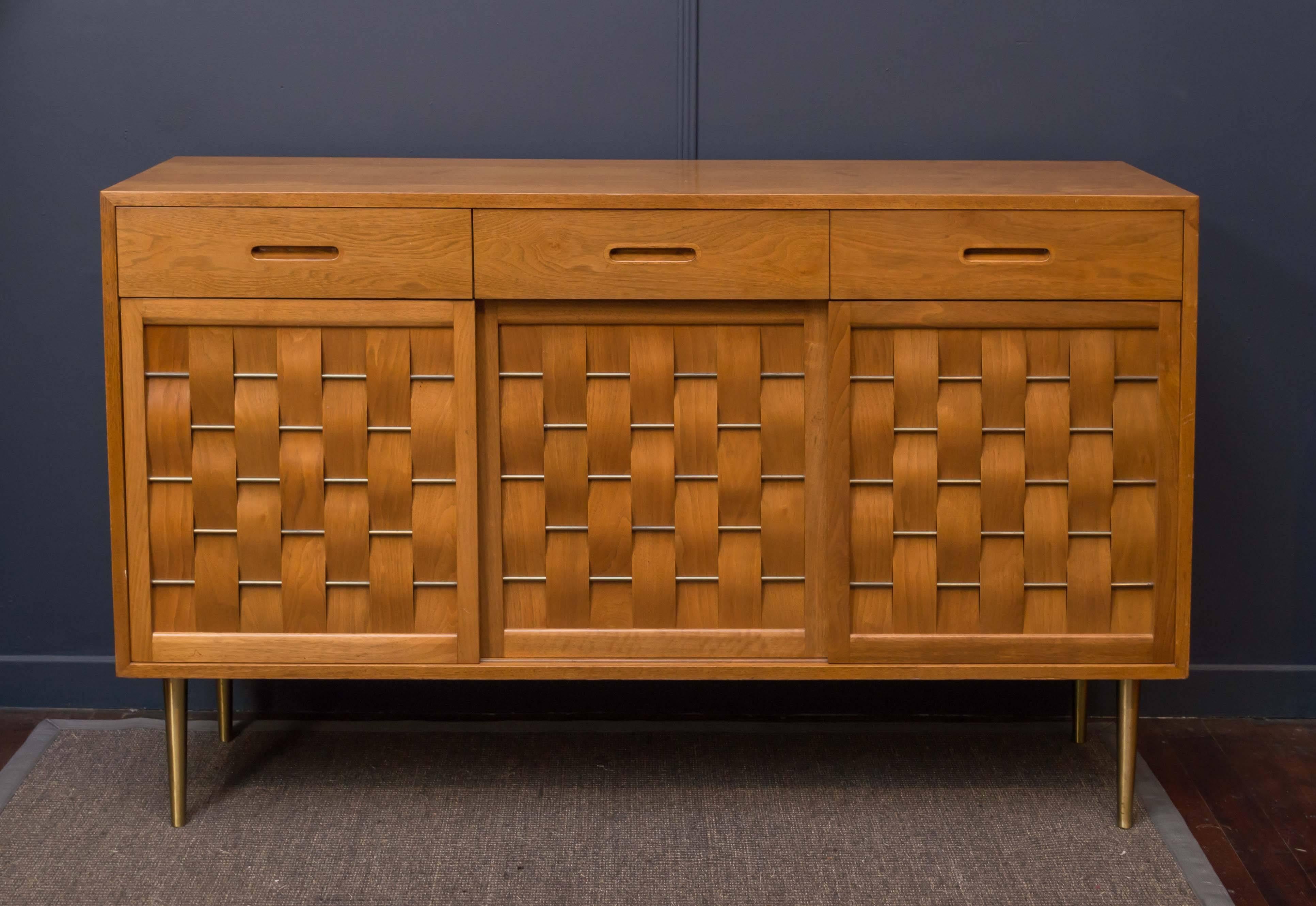 Edward Wormley design credenza for Dunbar Furniture Co. Three sliding doors with fitted interiors on original telescoping solid brass legs. 
Excellent original condition, labeled.