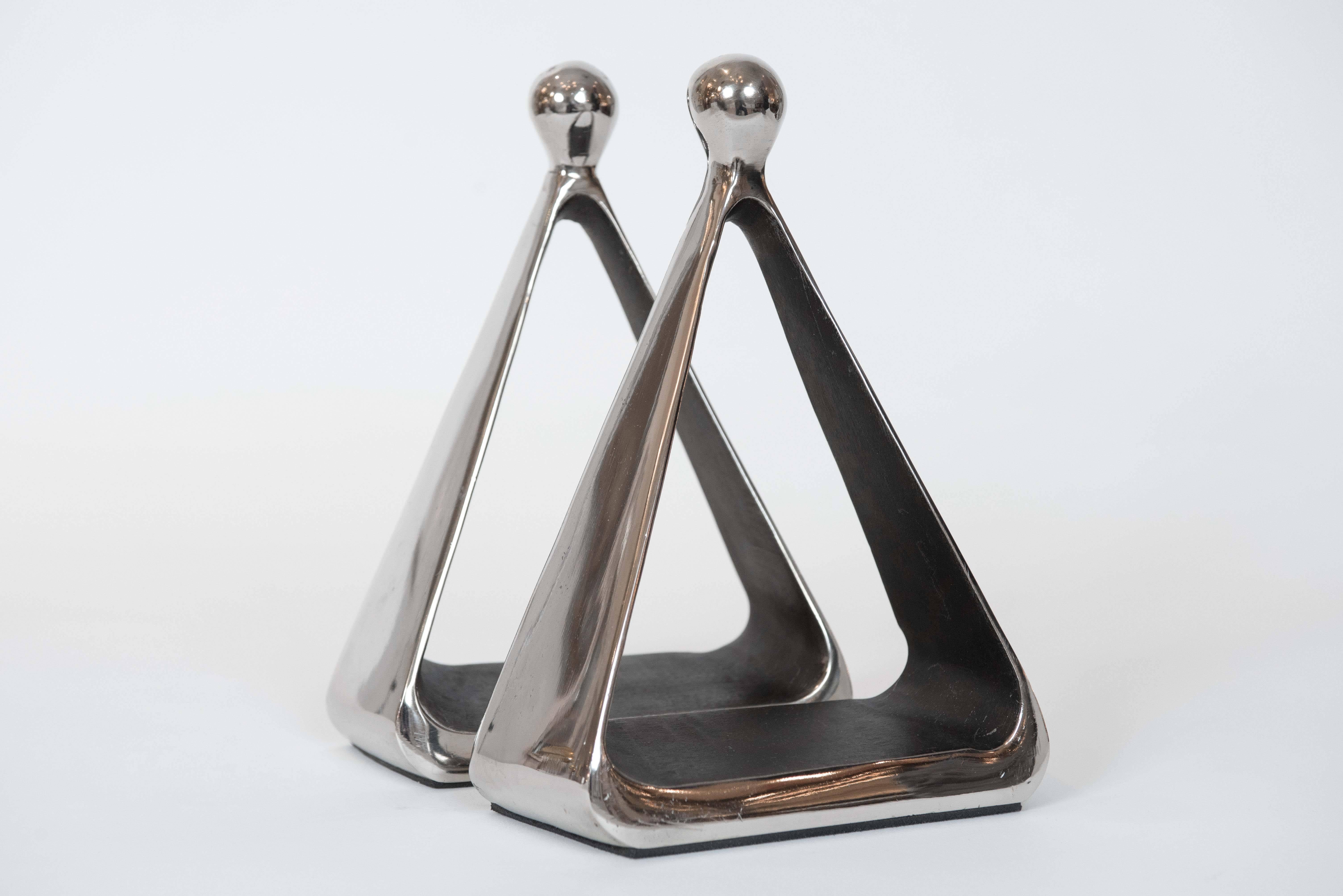 A sculptural stirrup style pair of bookends with chrome metal exterior finish and
a bronze colored interior.
