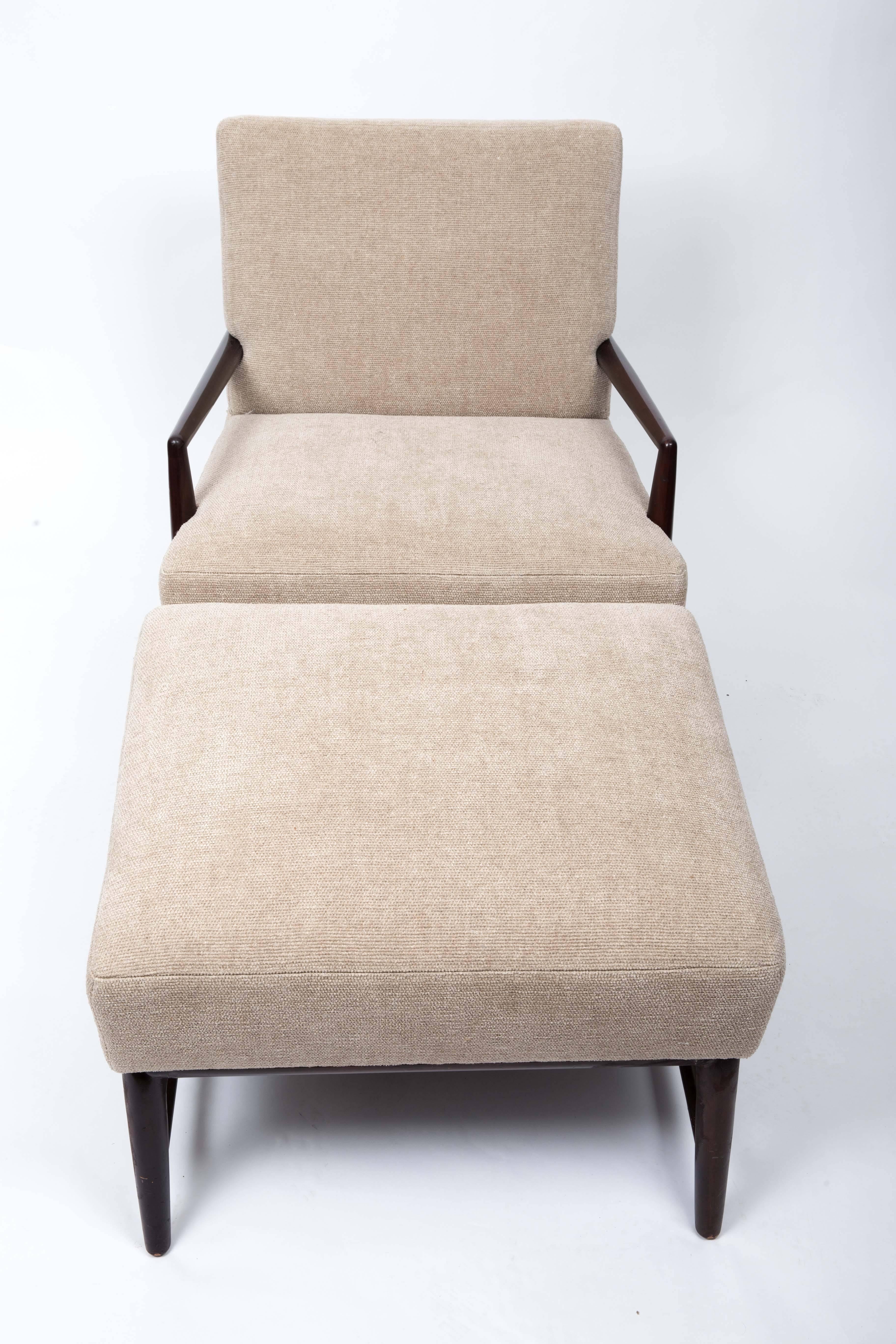 Classic mid-century armchair and ottoman by T.H. Robsjohn-Gibbings. 
Elegant wood frame, angular arms and legs, and brand new upholstery in a warm cream. 
