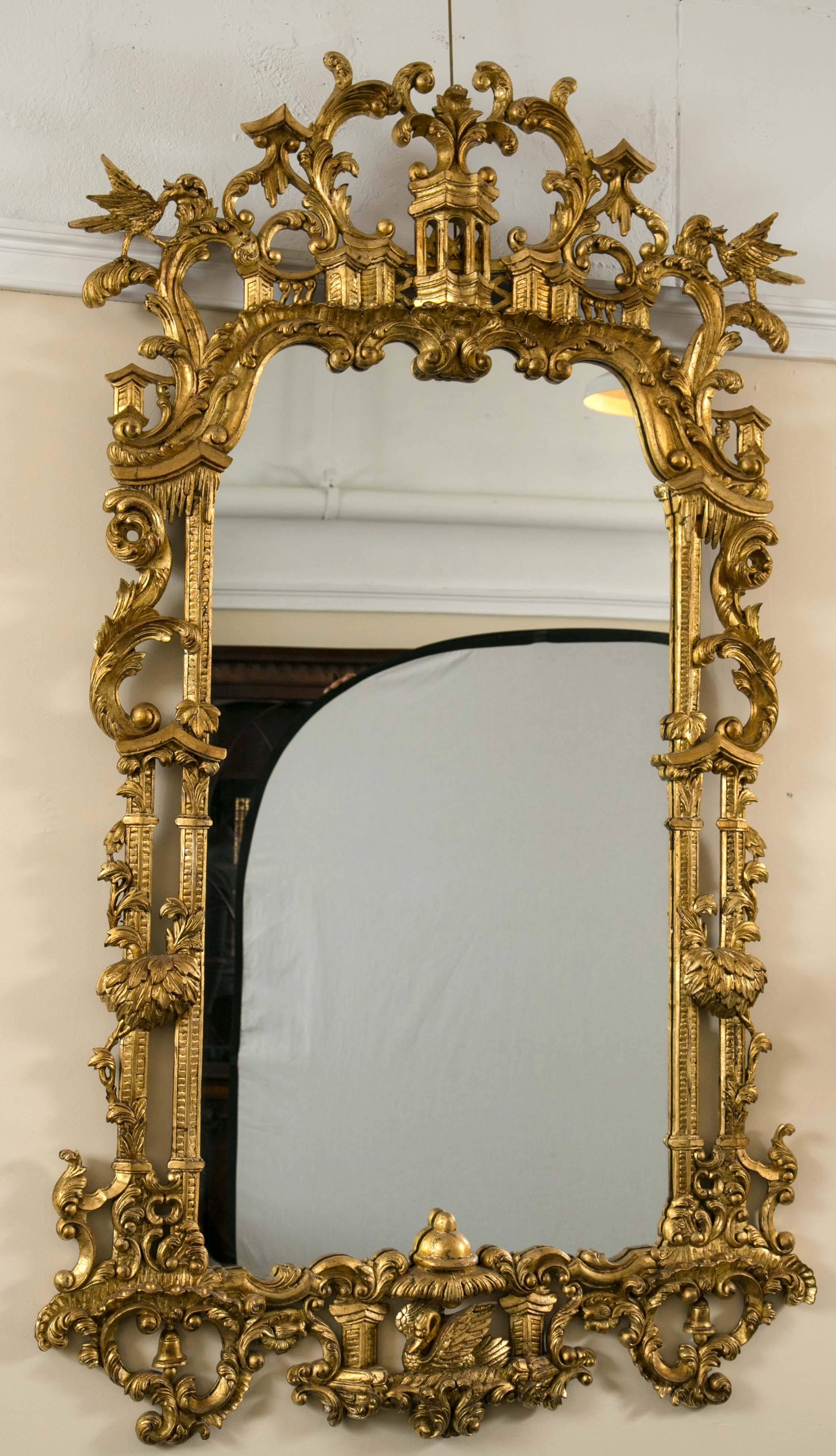 Pair of monumental gilt gold carved Chippendale style wall or console mirrors. The clear clean center mirror framed in a magnificently carved gilt wooden frame adorning Pagoda with leaves and foliage. The bottom of this finely worked frame having a