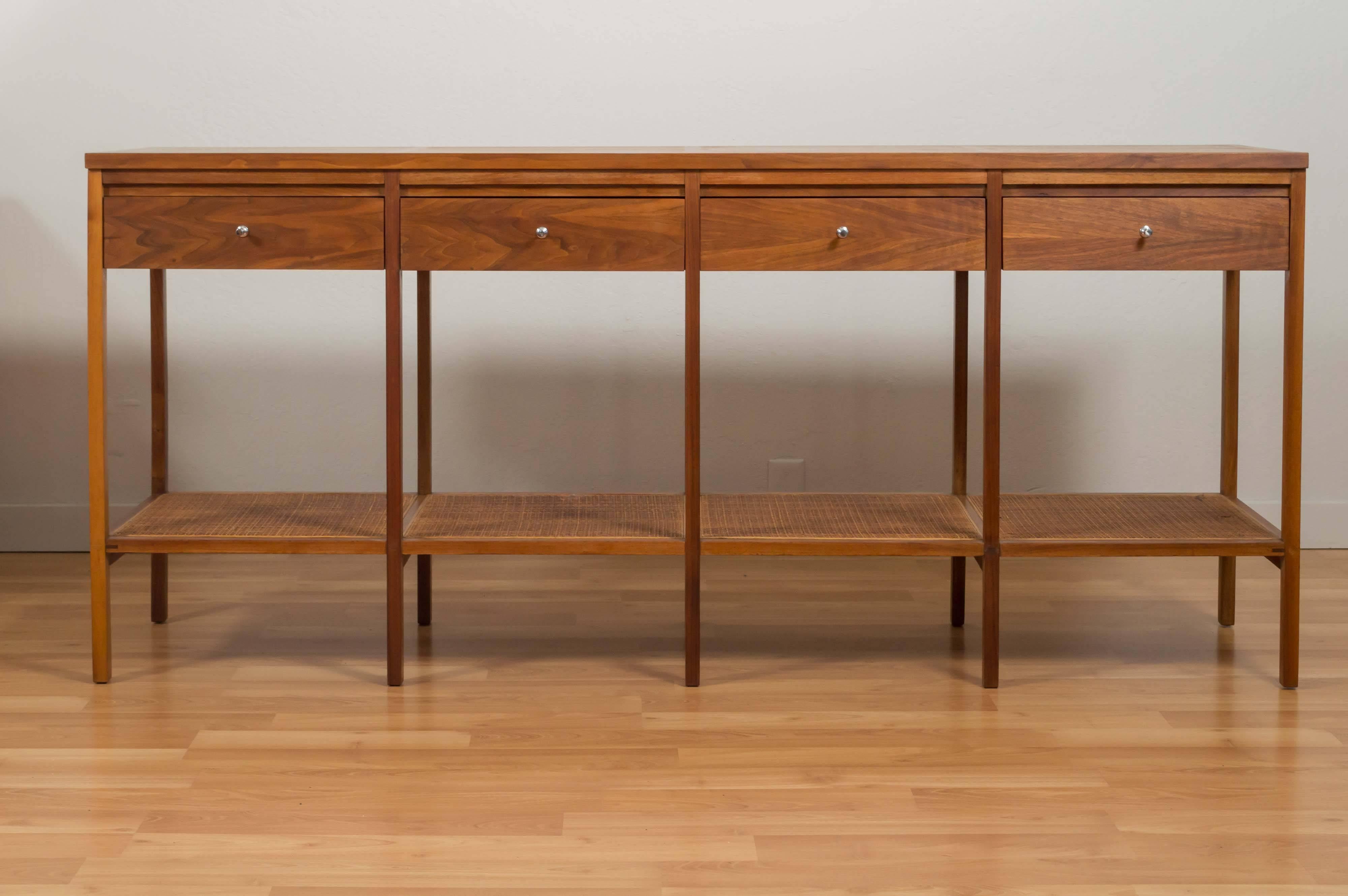 Handsome and rare four-drawer console or sofa table by Paul McCobb for Lane’s “Delineator” series. Wonderful looking four rosewood panels on top, then walnut frame and drawers, with original woven cane-covered shelf panels, and original polished