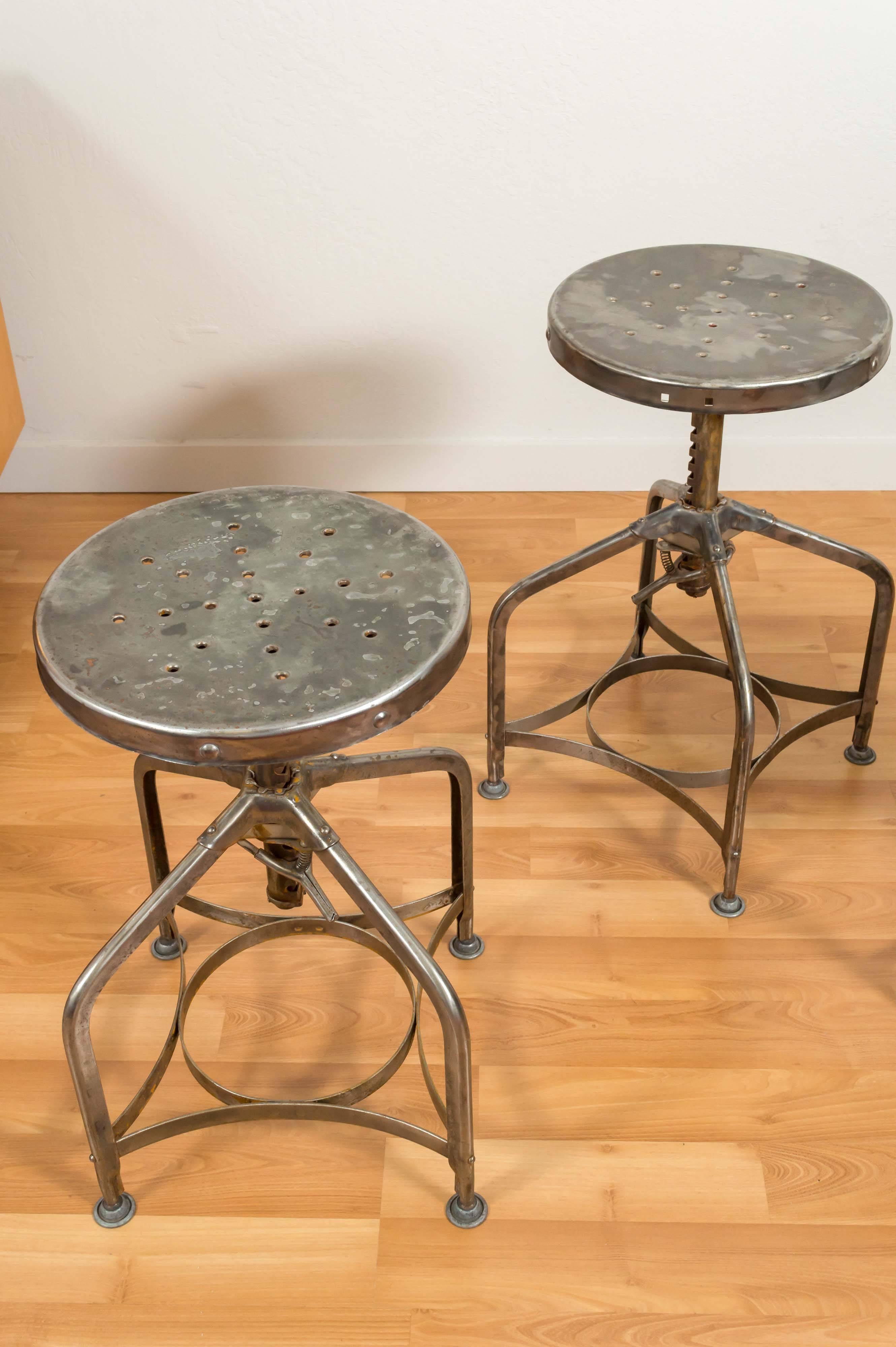 Only Two Left....  Toledo adjustable height (18 to 27in) swivel stools that represent unpretentious and functional American Industrial Design at its best. Originally painted beige, they were at some point sanded and buffed to reveal their steel