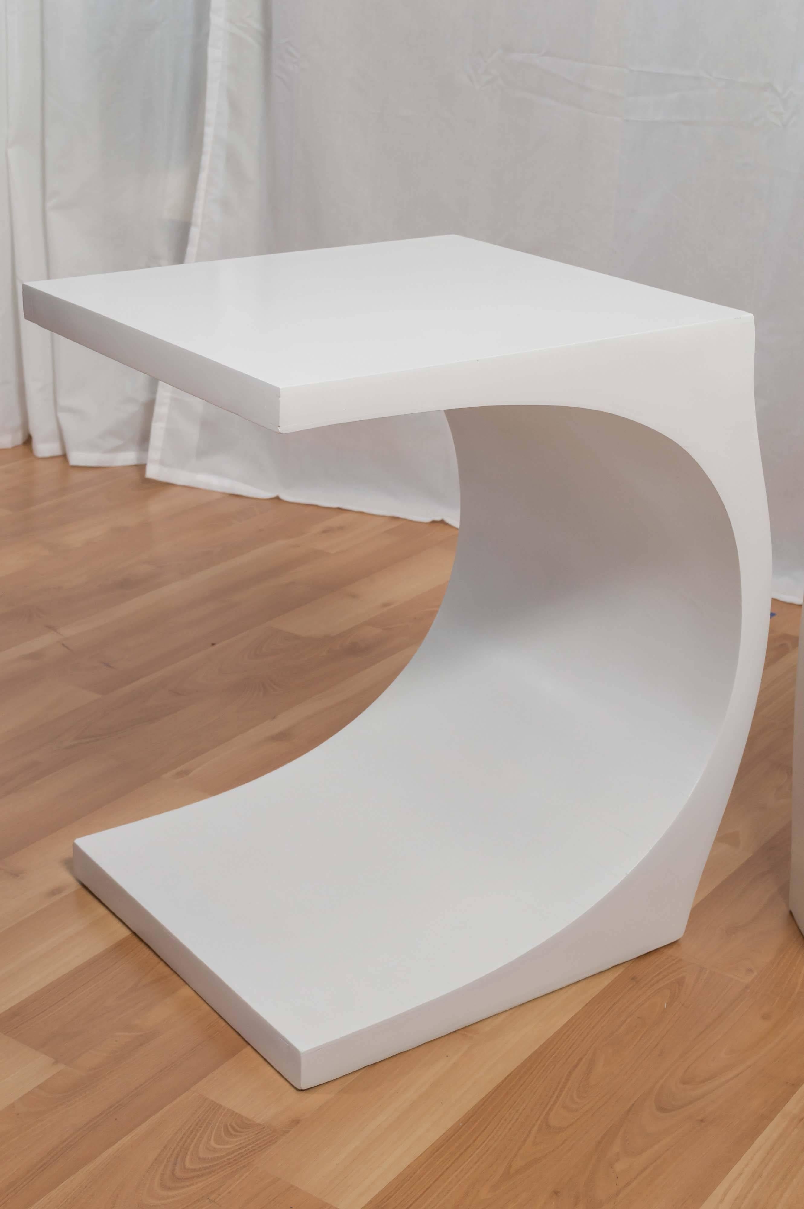 Uncommon modeline wood end tables finished in bright white lacquer that would pair perfectly with the sculptural lighting designer’s iconic “Cobra” floor lamp. 

The svelte tables give the playful appearance of buckling under the weight of