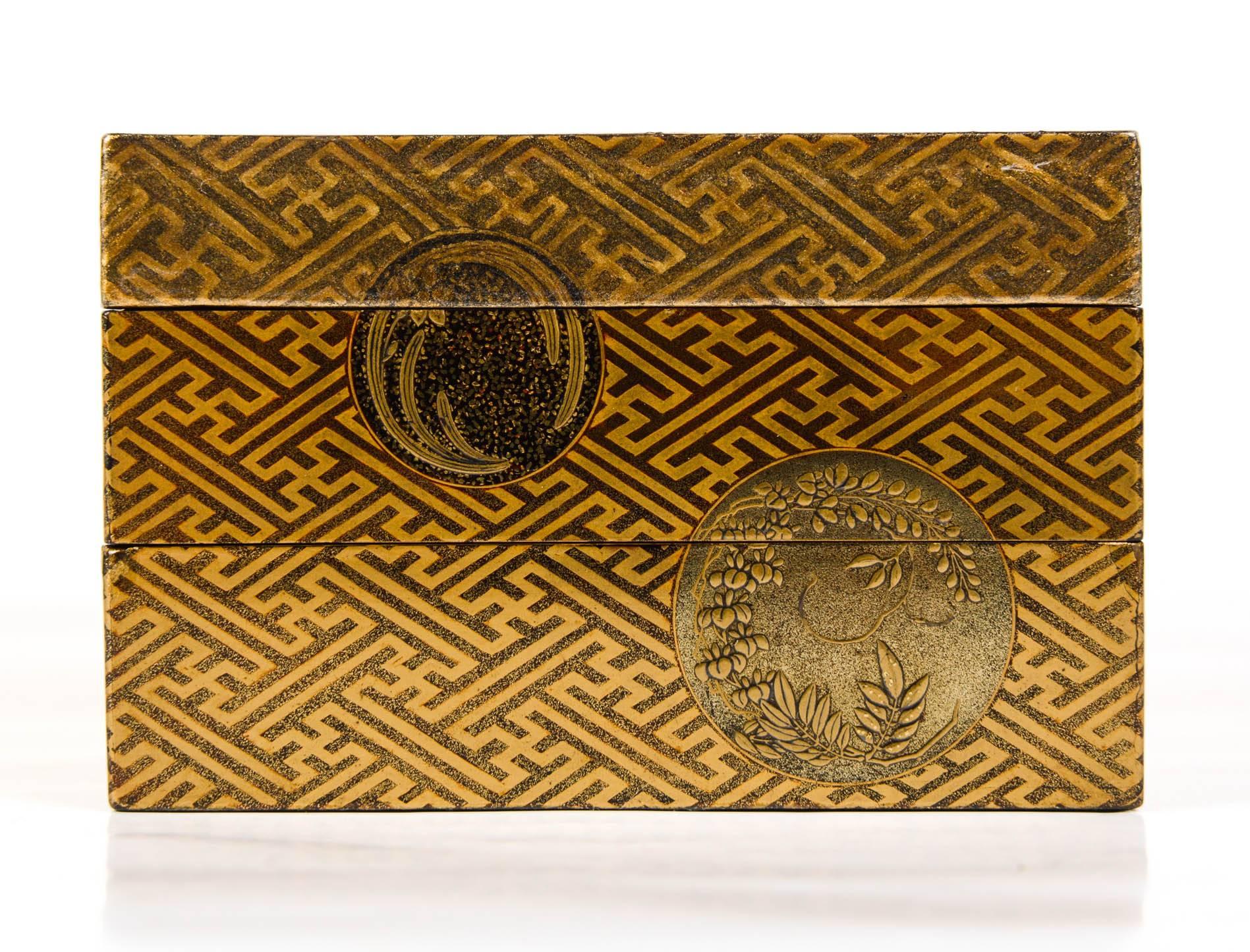 Kobako (box) with two trays depicting on the lid a embossed silvered decor of blossom cherry tress on a gold background, the sides decorated with geometric patterns and mons. The interior in nashi-ji lacquer. The second tray depicts two small gold