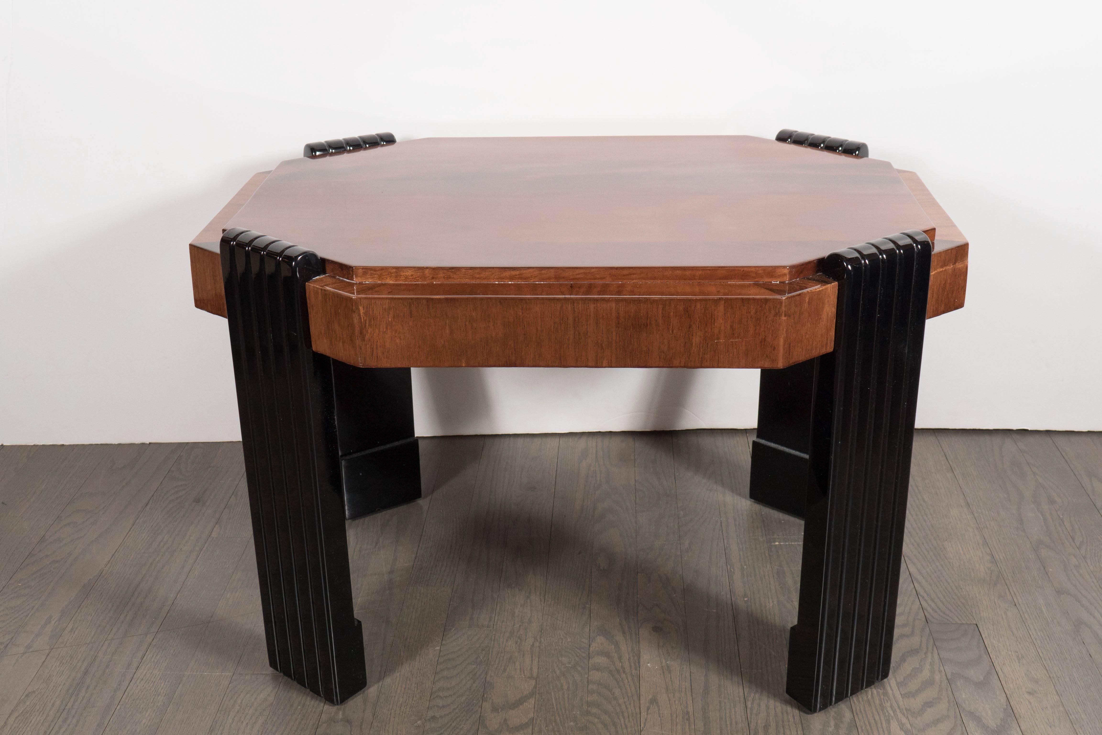 An Art Deco streamlined octagonal occasional table in burled walnut. Bookmatched detailing throughout, the top features a stepped border. Black lacquered legs with curved banded detailing support the piece. It has been restored to mint condition.