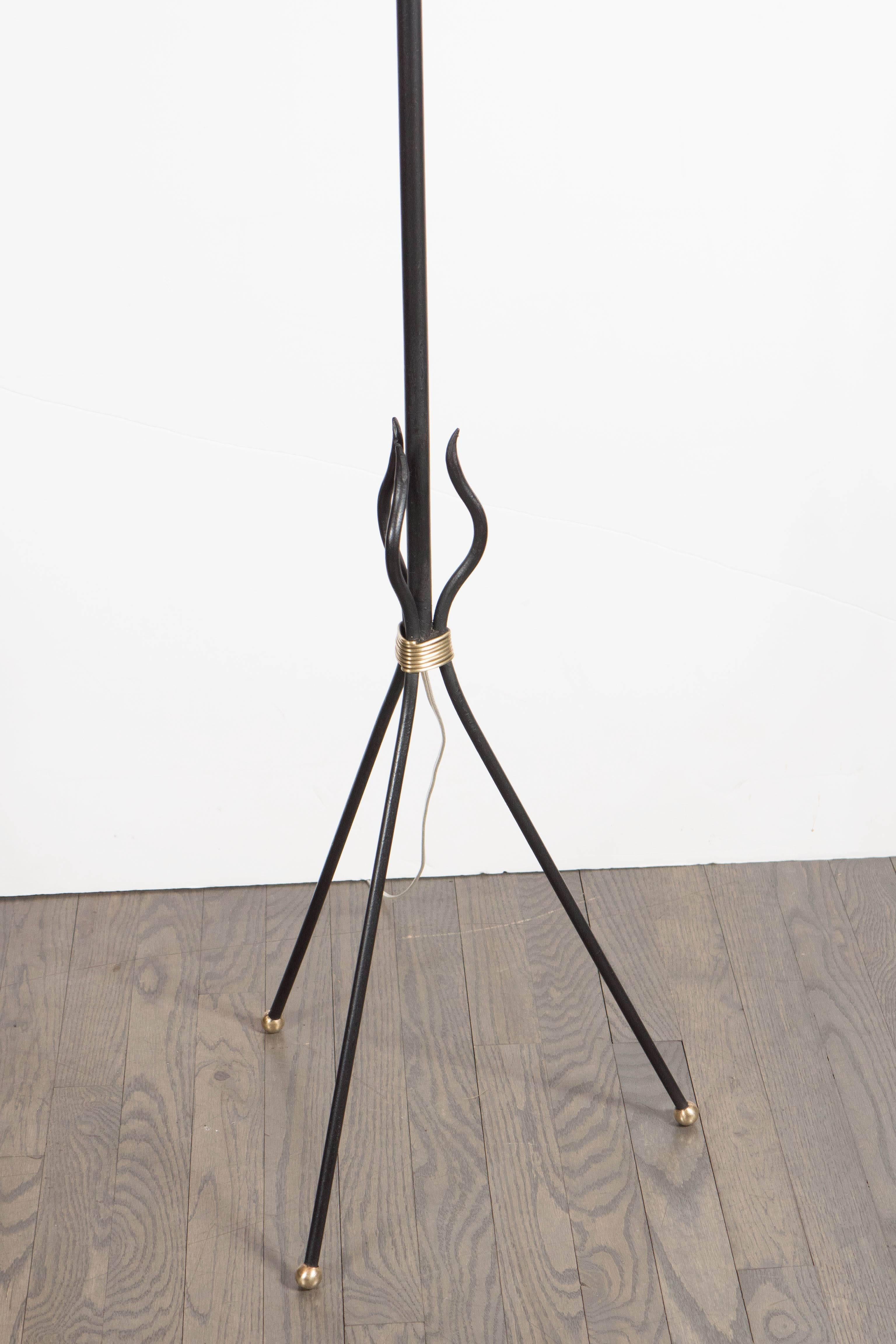 A sculptural floor lamp in wrought iron and bronze detailing, in the manner of Jean Royere. A tripod base with bronze ball feet supports a single stem which leads to a large sculptural folded shade. This piece has been completely rewired and is in