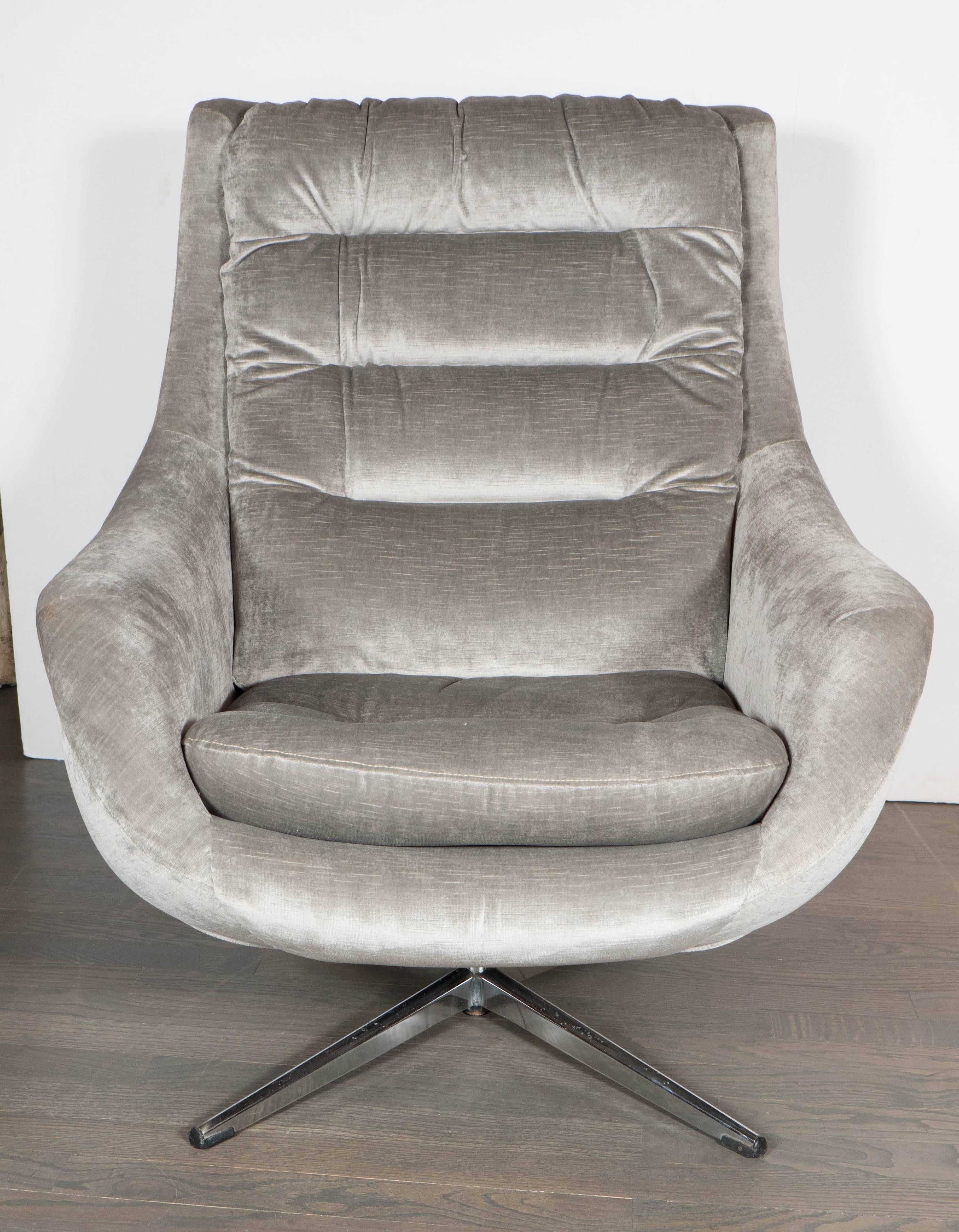 A chic Mid-Century Modernist curved high back swivel chair, newly upholstered in a luxe platinum velvet upholstery. Features a tufted back and seat cushion. A four-pronged steel base supports the piece. Wide, rounded armrests make for a very