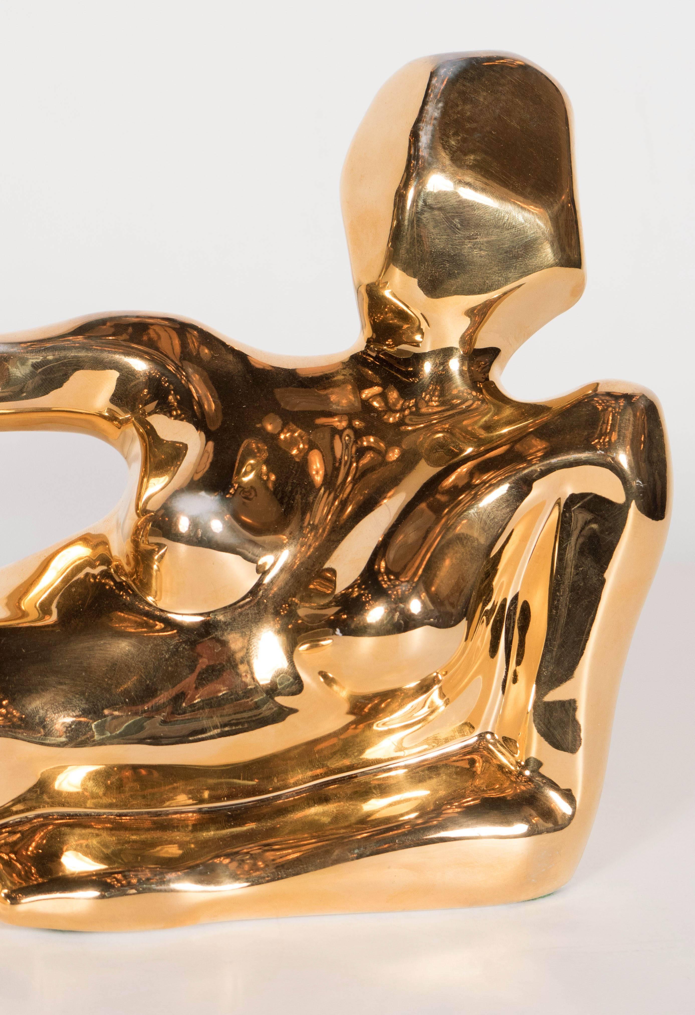 A chic Mid-Century Modernist figural sculpture in plated gold by Jaru of California. This example depicts a reclining woman in repose. The artist's nod to Cubism is apparent here as is a very slick, modern style. A lovely objet for any space. Signed