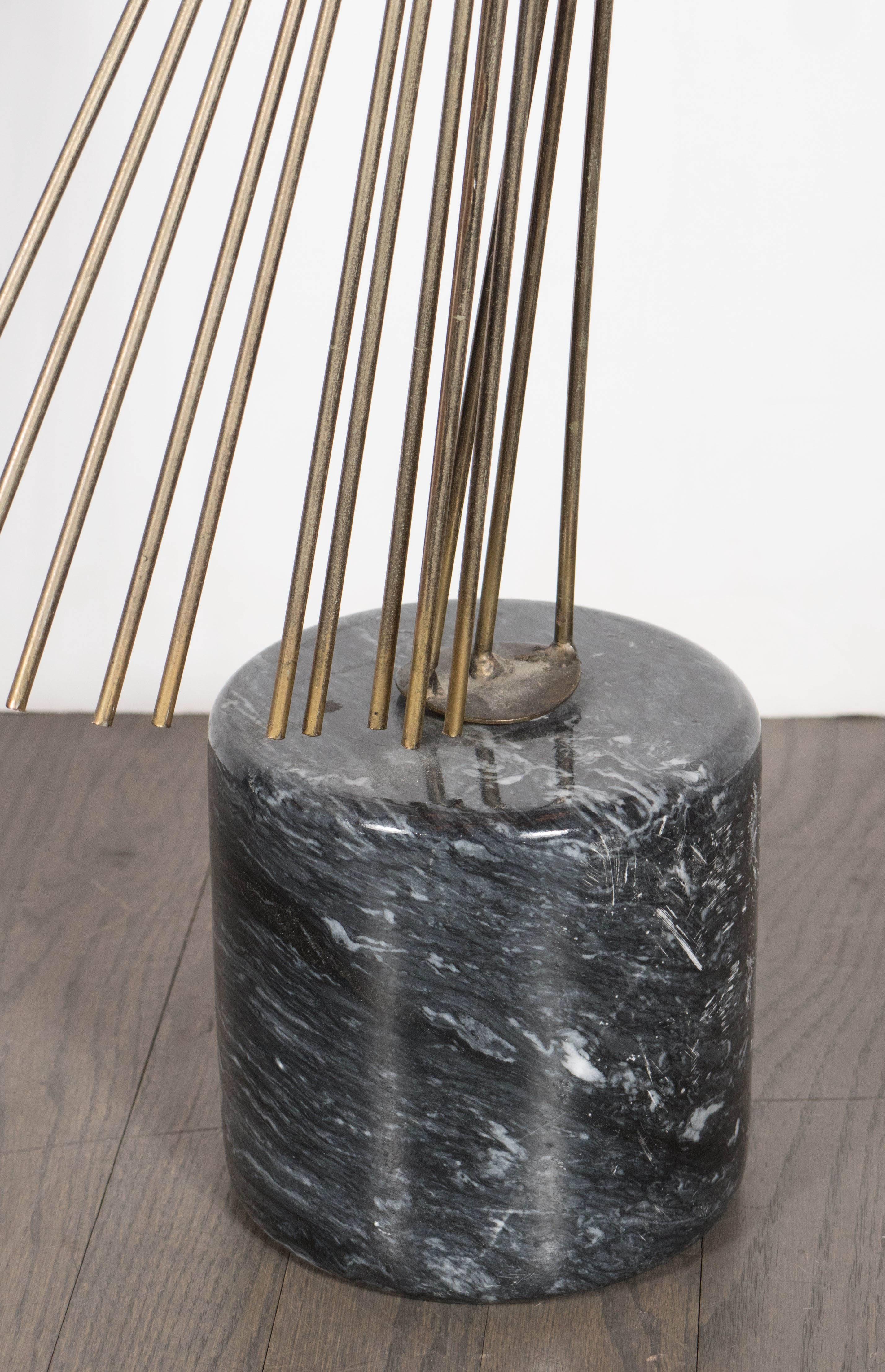 A Brutalist sculpture in patinated brass on a polished black marble plinth by Curtis Jere. A flowing sequence of brass rods connected at a central point depict a fan-like structure. Exotic black marble with white veining comprises the plinth. This