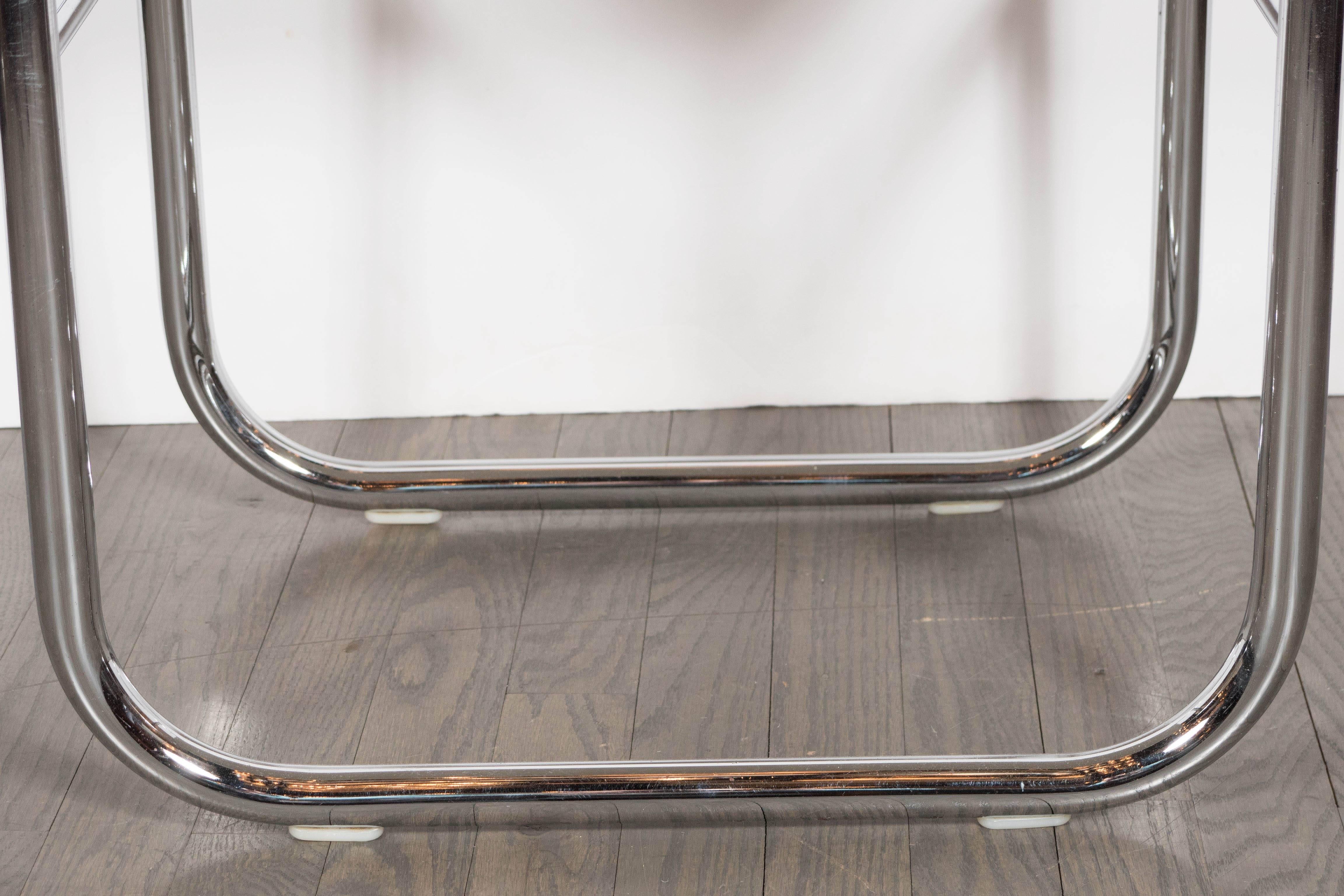 A Mid-Century Modernist polished chrome stool with wraparound ivory faux python-embossed seat. Cross-supports rest just underneath the seat of the piece. This piece would live nicely in a master bathroom aside a bathtub or shower. This piece has