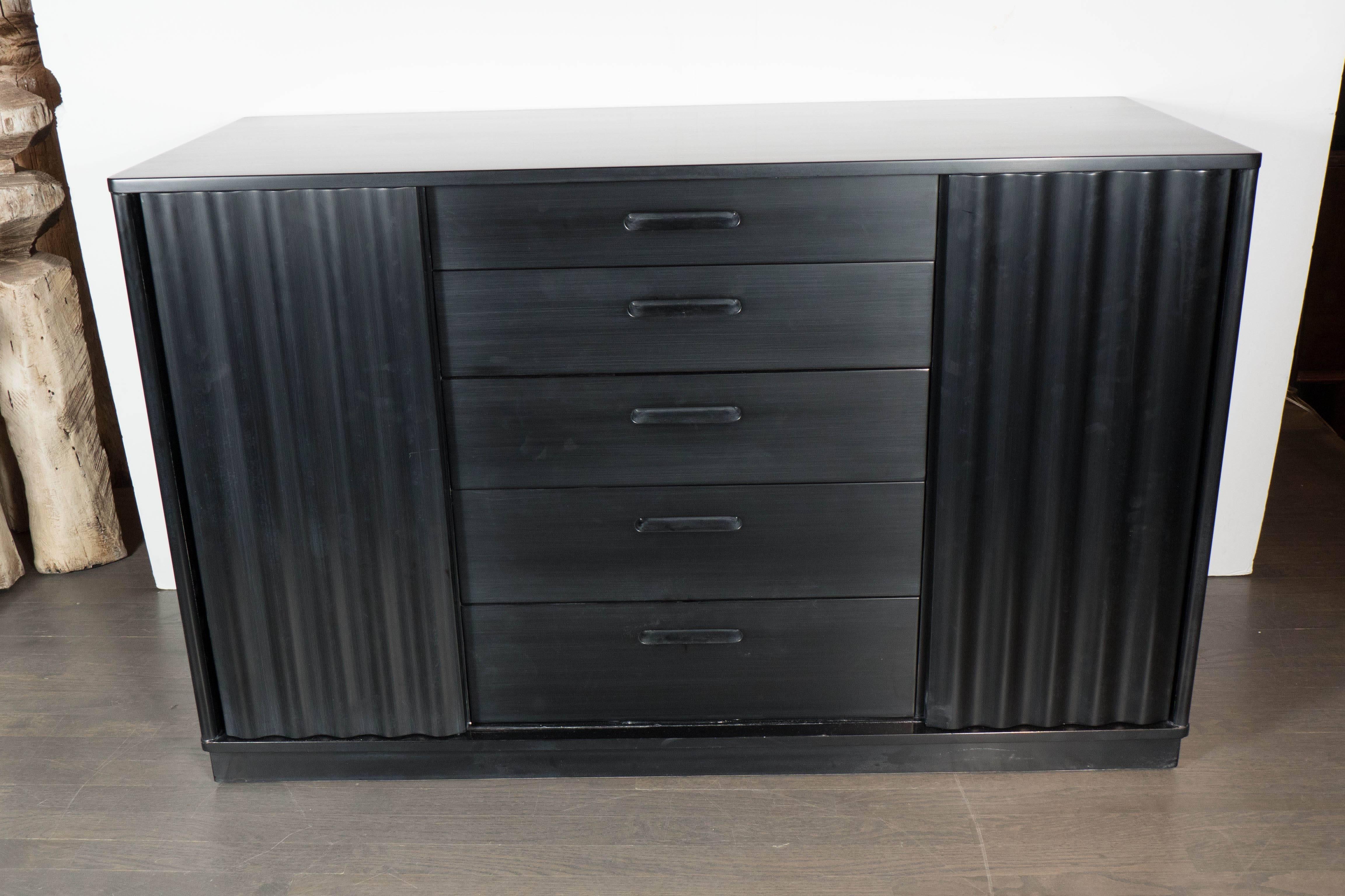Gorgeous Mid-Century Modernist chest or credenza in ebonized walnut by Edward Wormley for Dunbar features five drawers centrally positioned between sliding cabinet doors with a fluted design, the cabinets have adjustable interior shelving. A