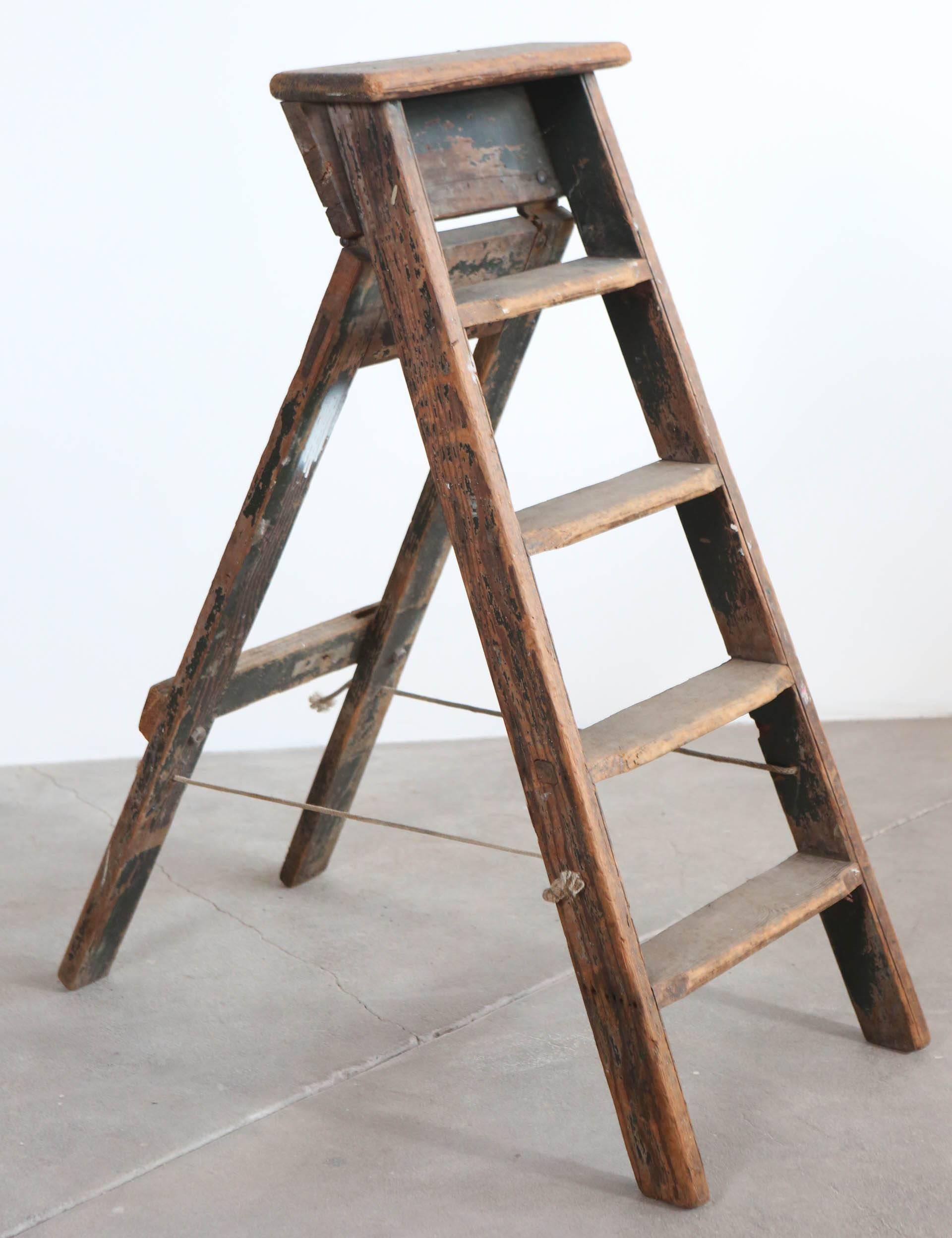 Rustic five-step wooden ladder with rope hinge.