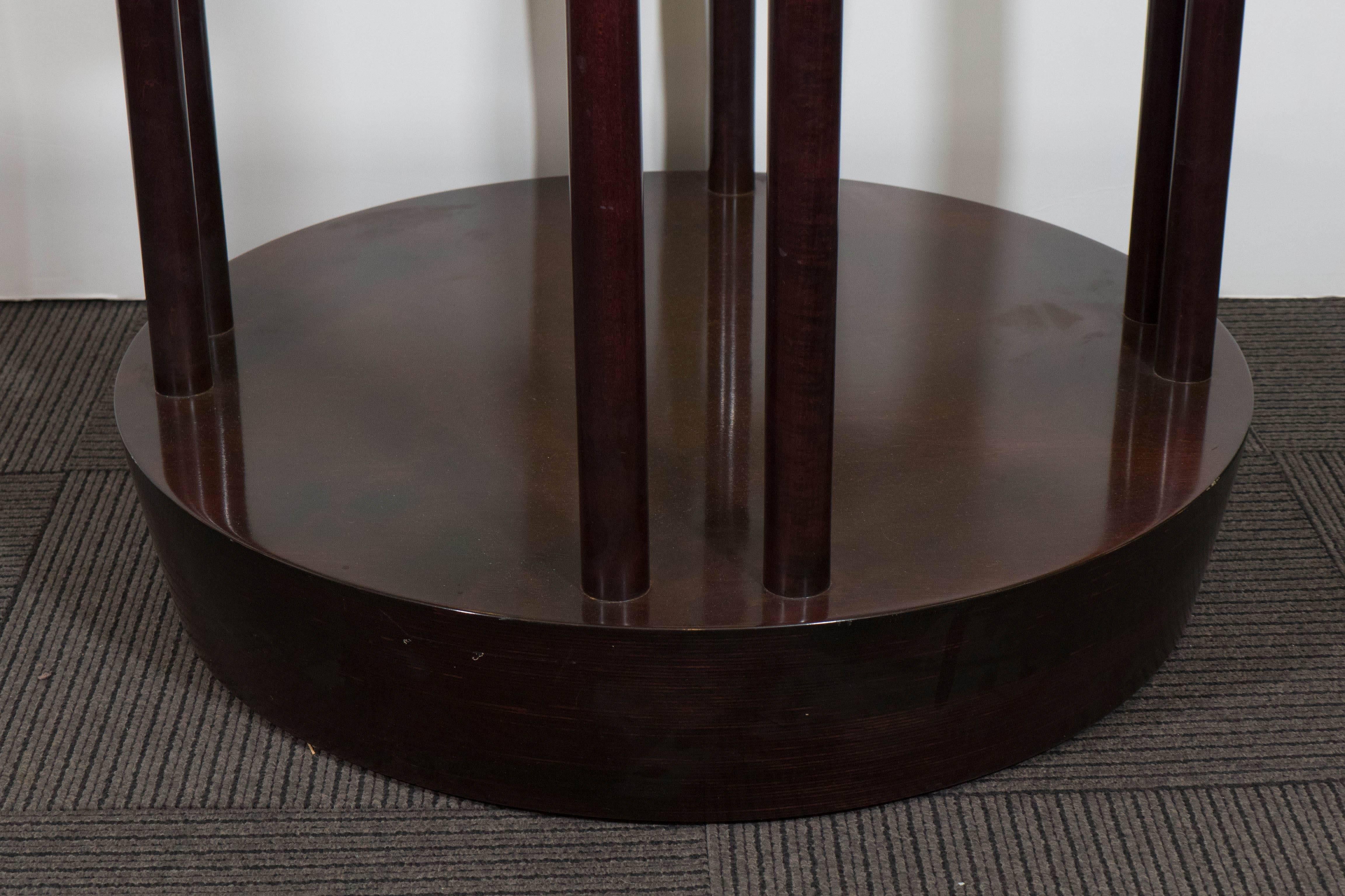 A round occasional table in richly toned wood, in the style of Josef Hoffmann's early 20th century designs for Cabaret Fledermaus of Vienna, with ring form top, supported by eight pole legs, separated into pairs with ball motif, on a thick