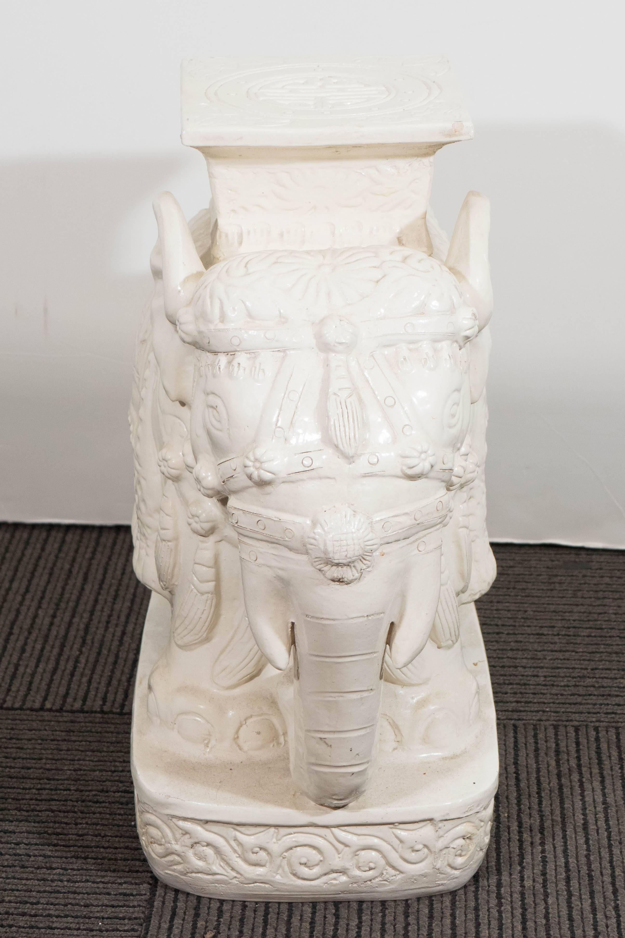 A pair of vintage Asian inspired elephant garden stools, each in ivory toned glazed terracotta, with incised details. The stools remain in good condition, with age appropriate wear, including some small chips to the finish.