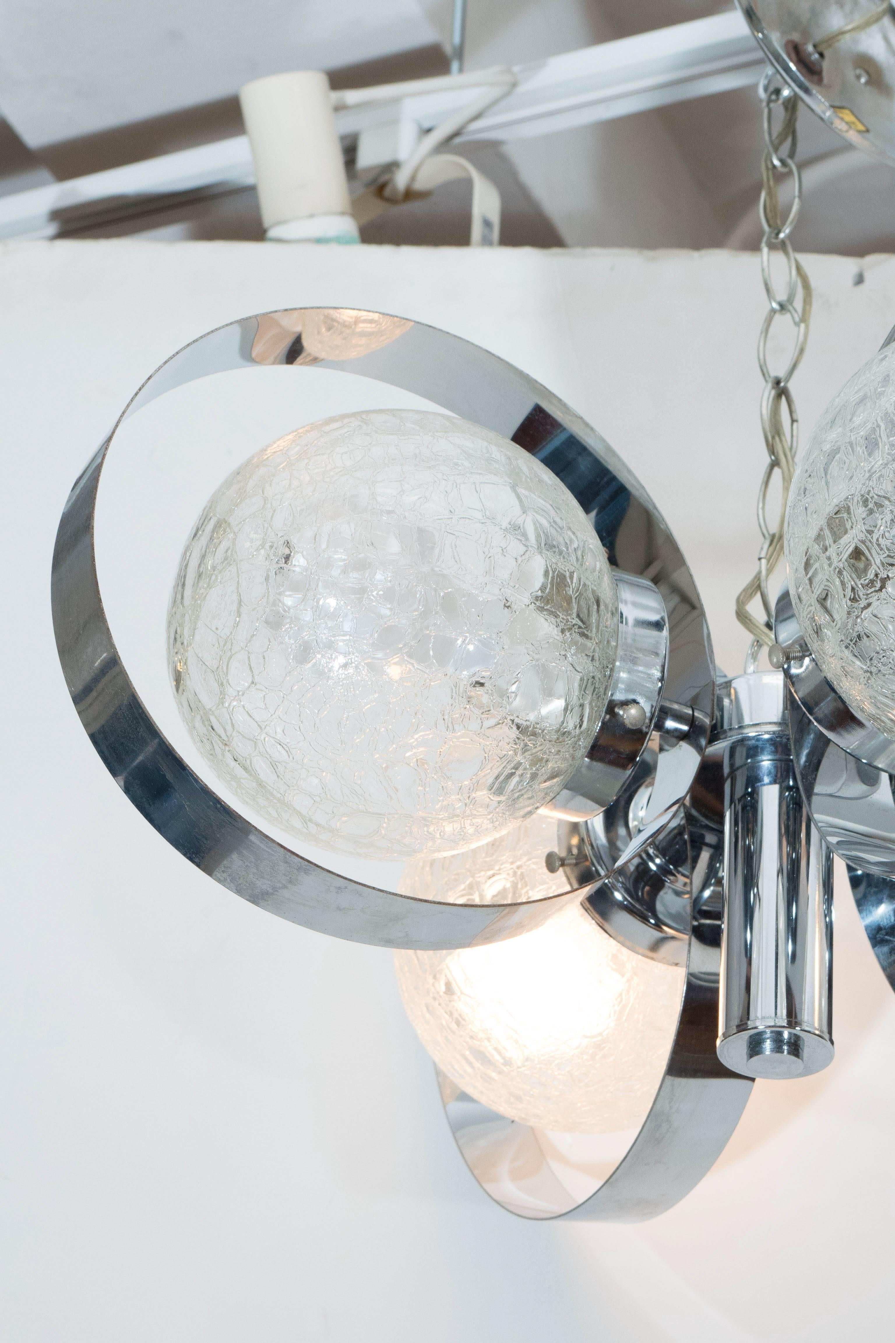 This highly modern Italian chandelier, produced, circa 1970s, includes four lights, affixed to a central cylinder, each individually surrounded by crackle glass globes and a polished chrome ring. The chandelier remains in very good vintage