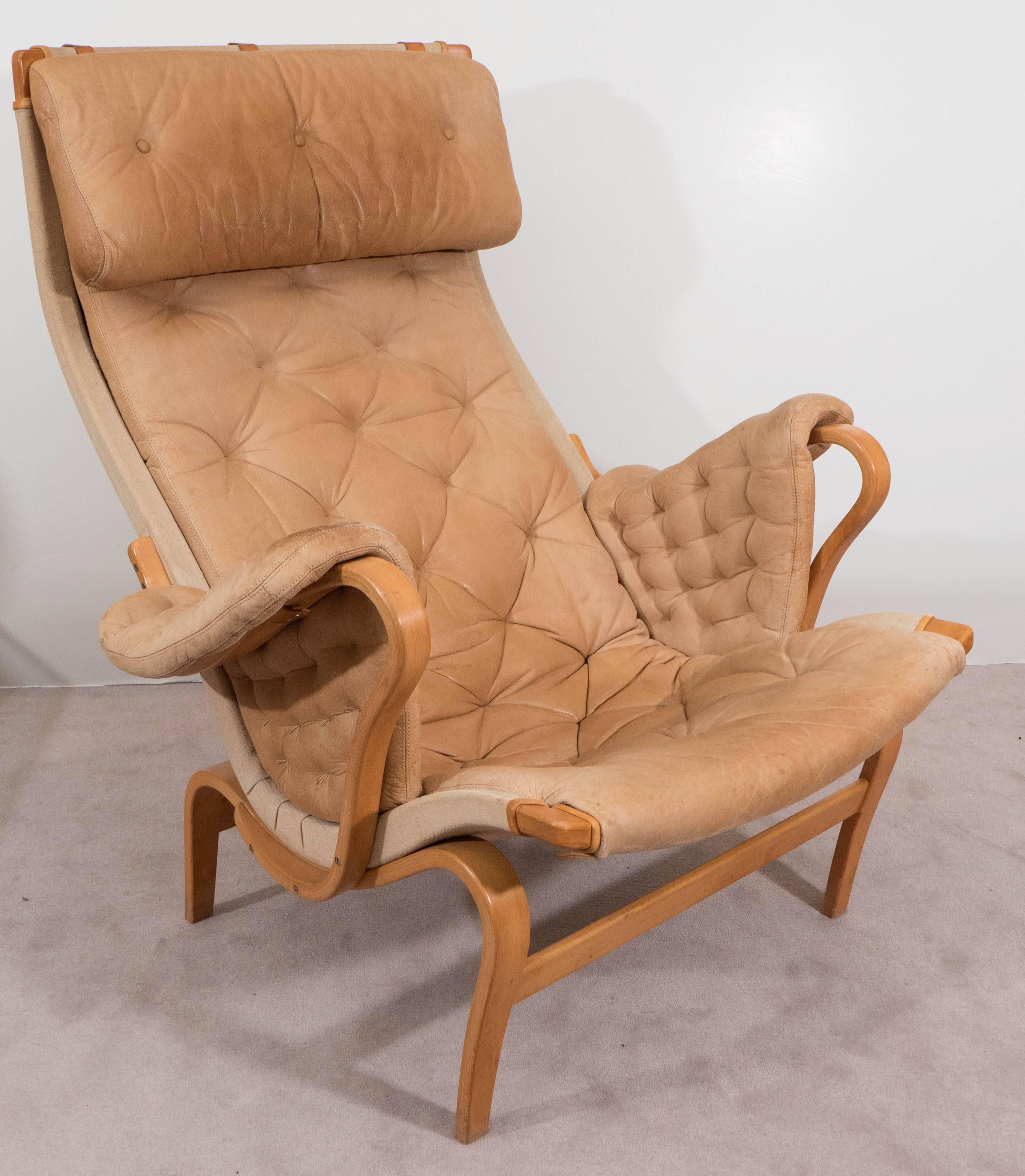 This Bruno Mathsson 'Pernilla' series lounge chair, produced by DUX circa 1970s, comes with cushioned seats and headrests in tufted tan leather, against linen and bentwood frames in beech. Markings include [Bruno Mathsson by DUX] stamped to the wood