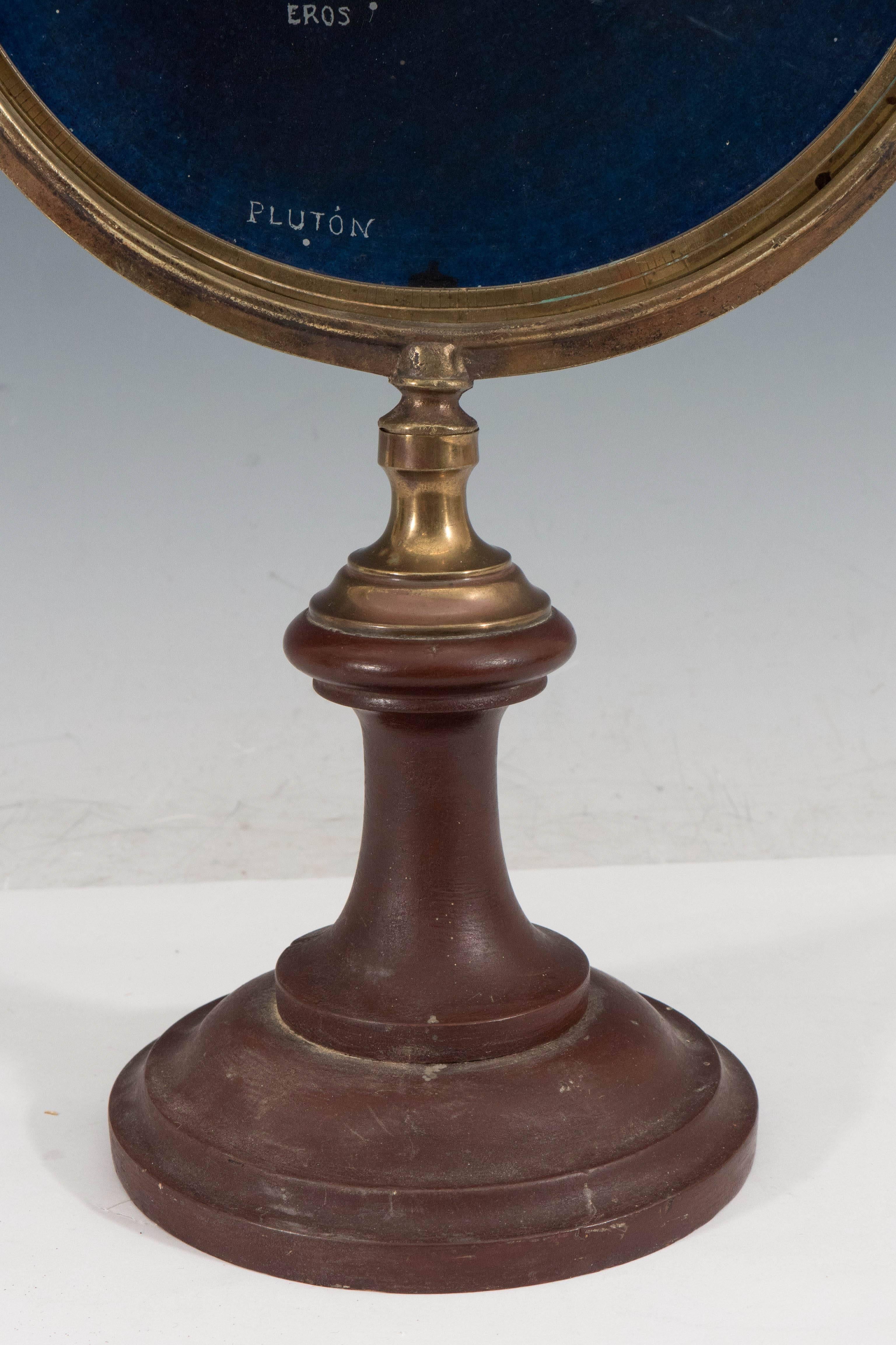 A unique astrolabe, with reverse hand-painted glass disk, depicting a pictorial view of the solar system, the sun and surrounding planets (written in Spanish), as well as the asteroid Eros, against a deep blue ground. The disk is set against a brass