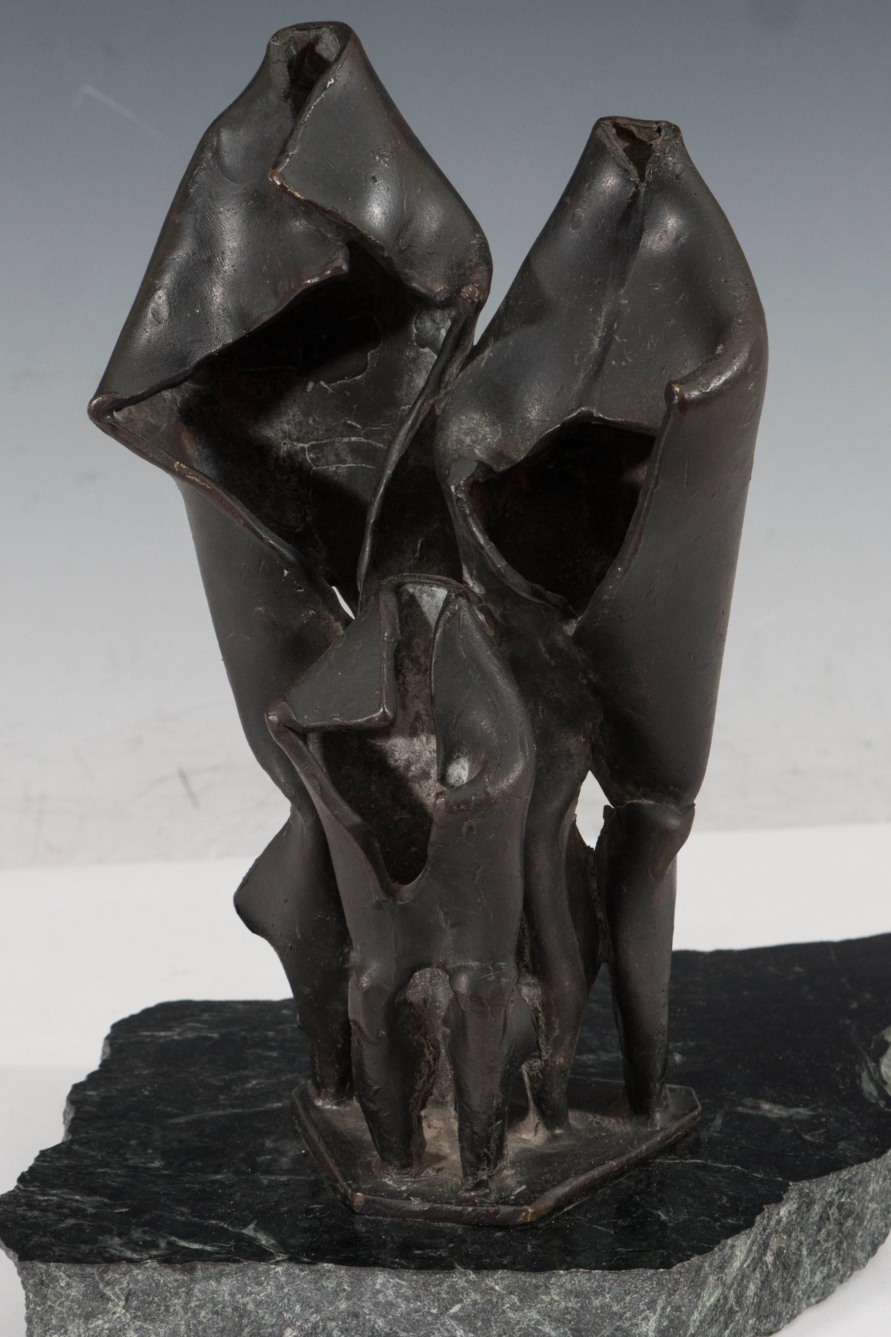 A vintage Brutalist style abstract sculpture, produced by an unknown artist, in patinated bronze, formed into three shapes resembling figures, mounted off-center on a raw edge black marble base. The sculpture remains in good condition, with age