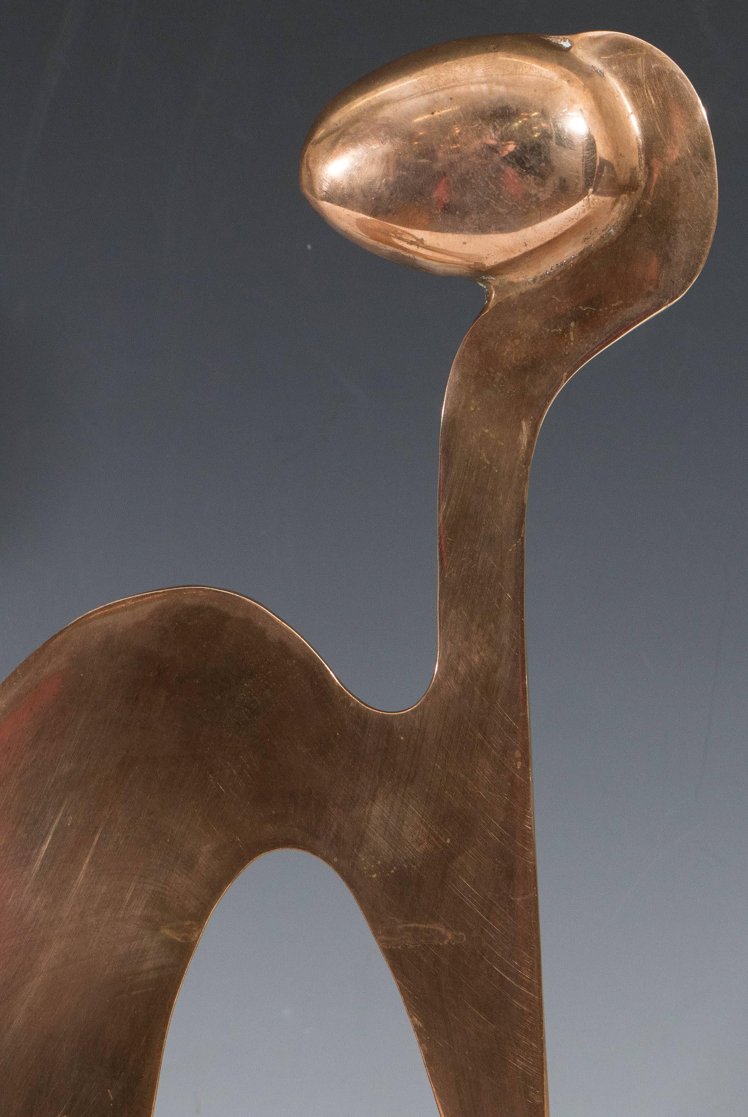 An abstract sculpture of a reclining figure in polished brass, by collaborating artists Arleen Eichengreen and Nancy Gensburg, circa 1970s. The structure of this sculpture, rounded head over a contorted flattened body, creates a fascinating sense of