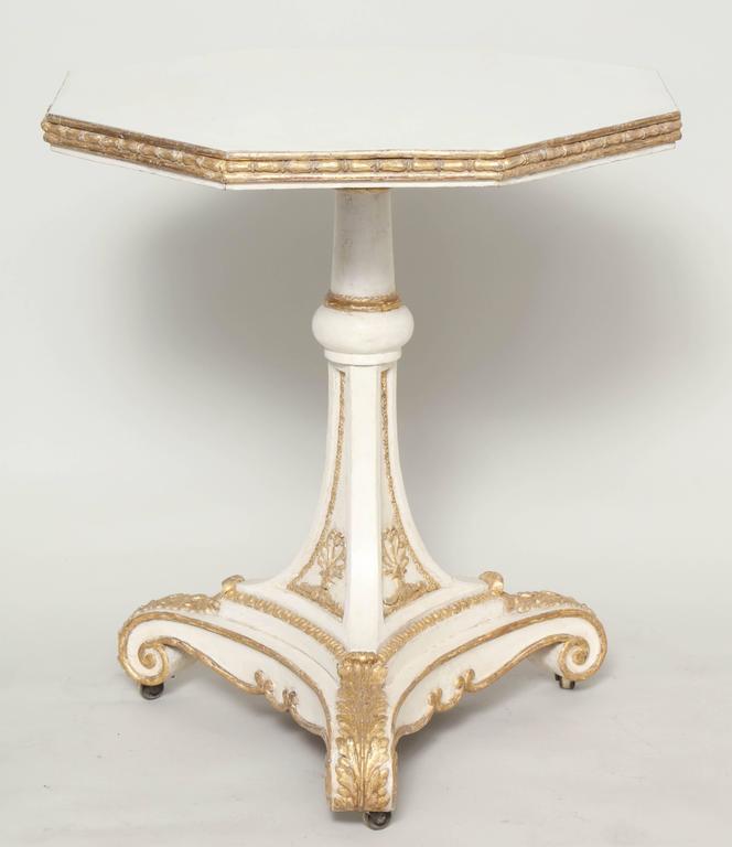 A striking end table with gilt trim on white ground having an octagonal top and a pedestal base with castors, English, circa 1820.

 
