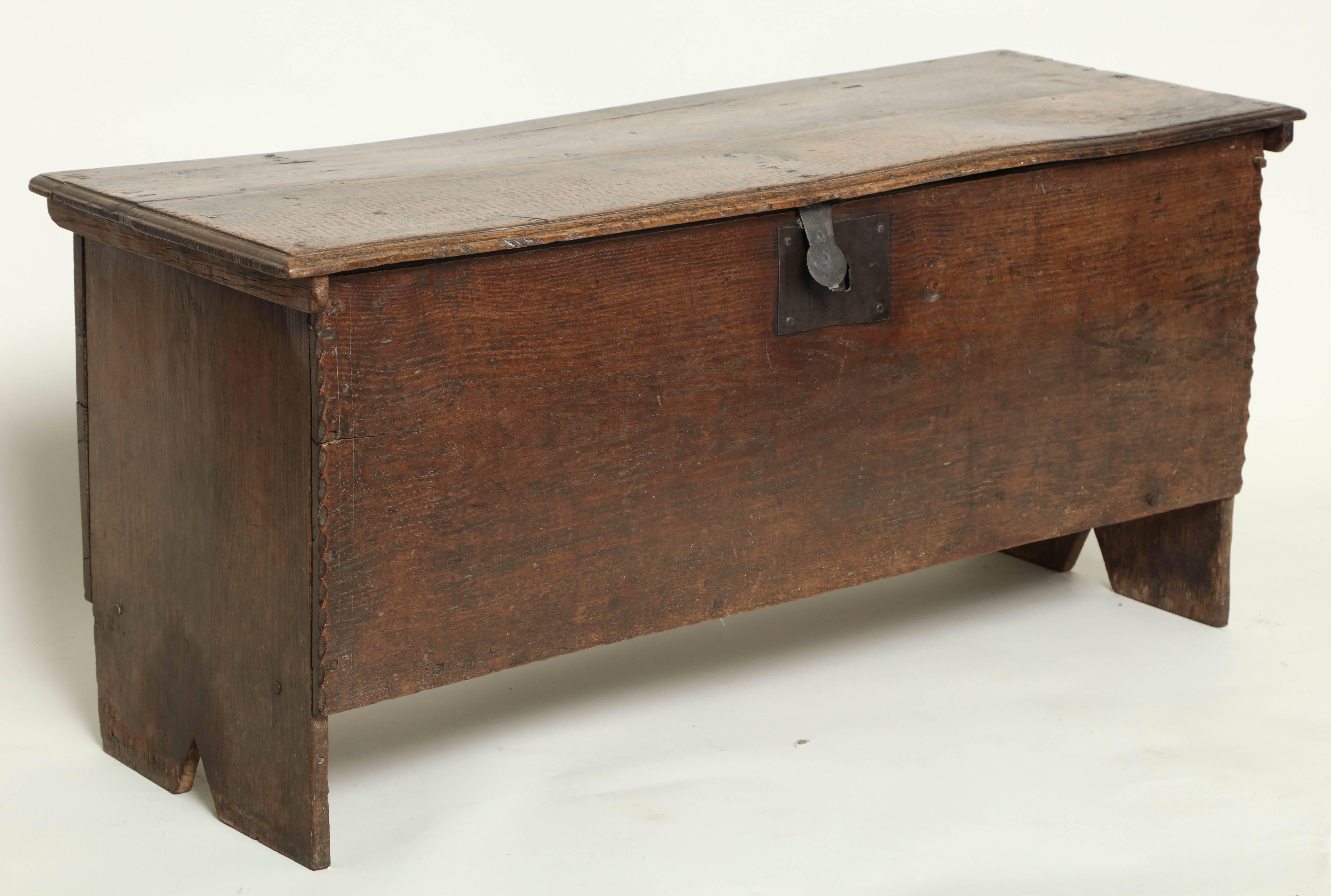 Good early 18th century oak six plank coffer with molded top over boot jack ends, the front with chip carved edge and original wrought iron escutcheon, the whole with rich, faded surface and patina.