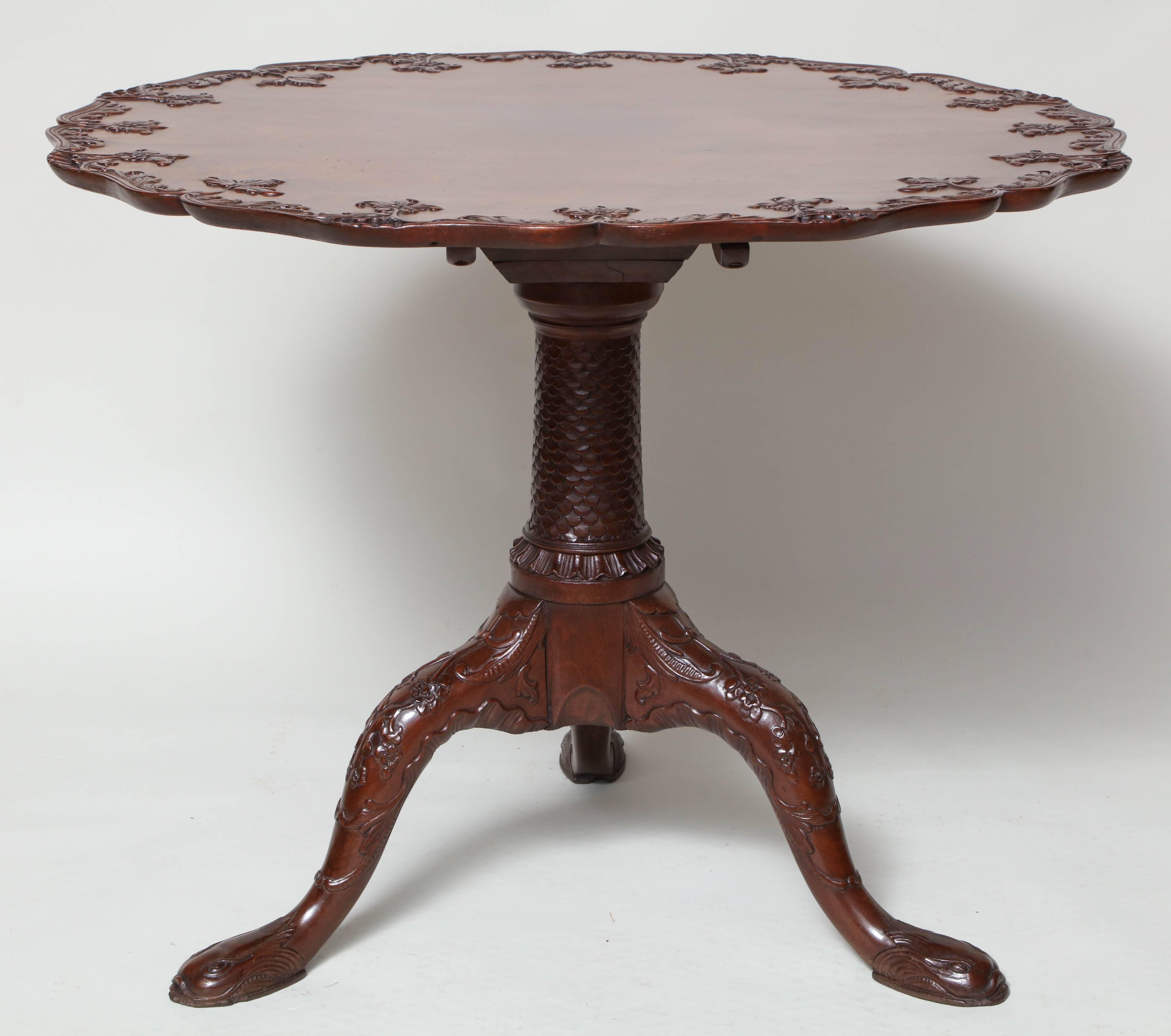 Very fine 18th century padouk tilt-top table with foliate carved scalloped single board top over scale carved shaft with pagoda base over three cabriole legs with foliage and vine carving ending in dolphin carved feet.