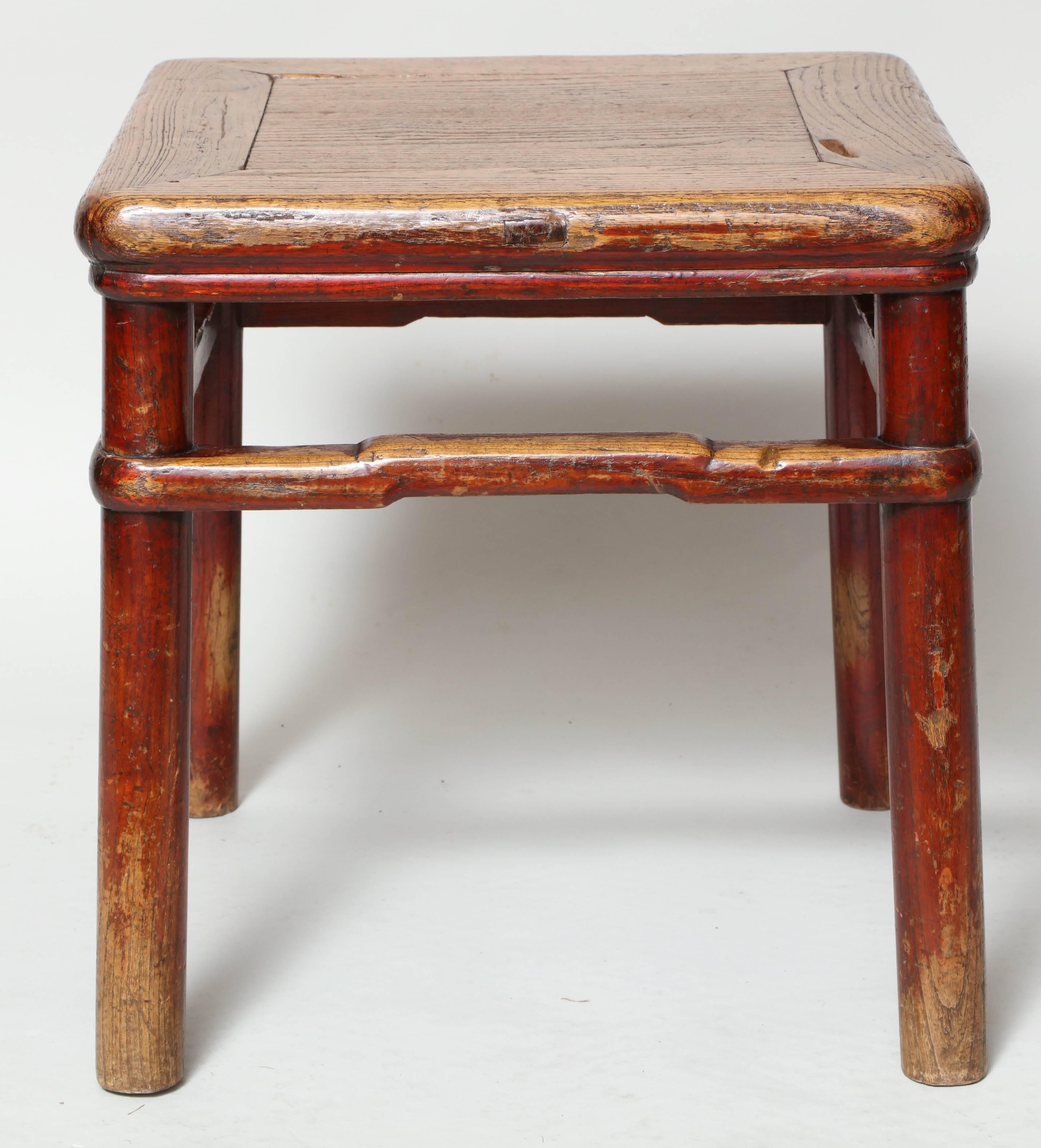 An early 19th century Qing dynasty stool or small table in elm, beautifully crafted of a mitred top with rounded edges on four slightly splayed spoke legs joined by high box stretcher that wraps around each of the legs and features a raised center