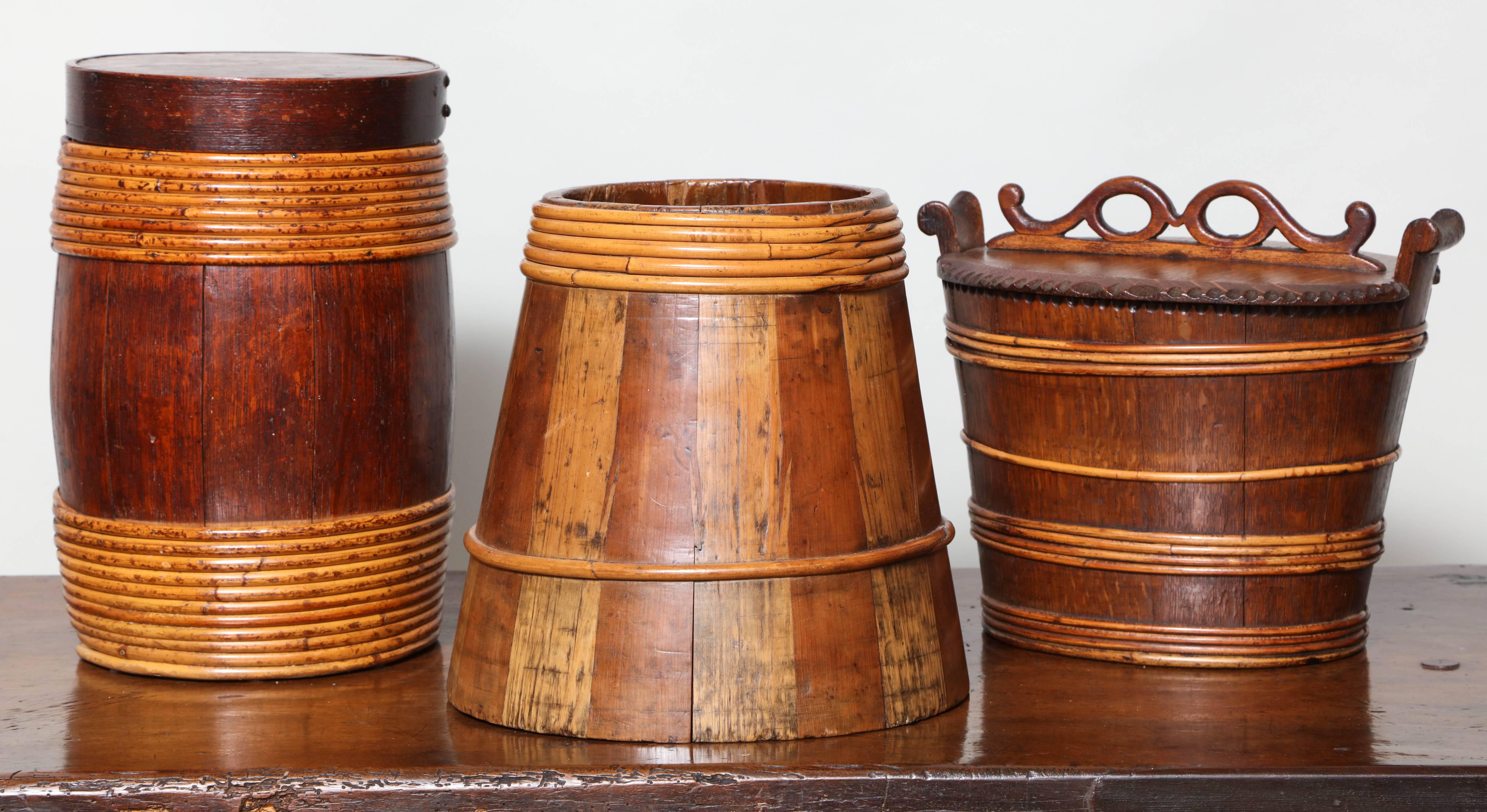 Collection of three 19th century willow banded treen vessels comprising:

A Scottish firkin in mixed woods, alternating pine (light) and fruitwood (dark) having feather joints holding the staves together and bound with willow, Ex. Collection A.J.