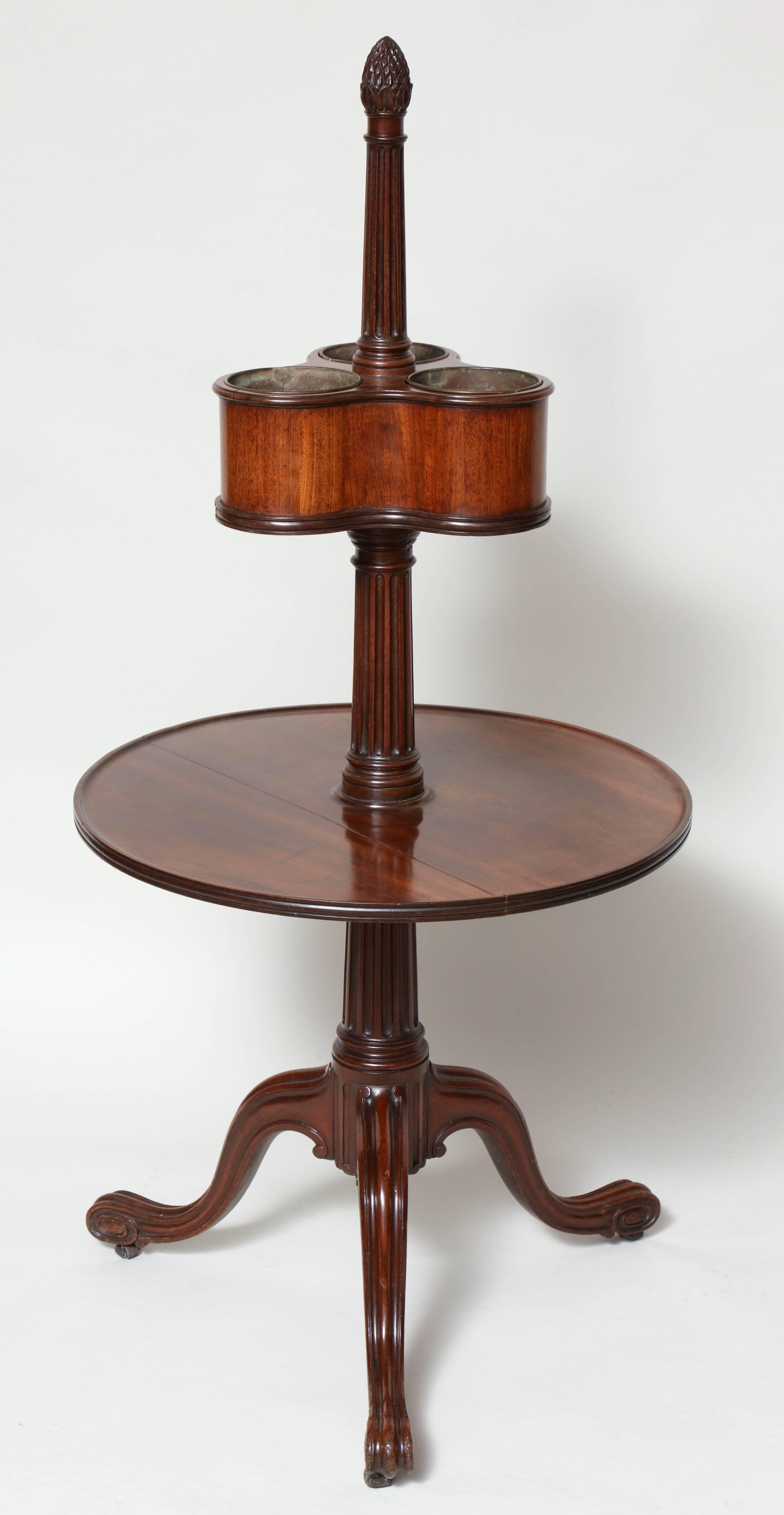 A possibly unique George III wine stand in the manner of Thomas Chippendale, the pineapple finial over fluted column over three chamber bottle holder with original brass liners, the edges deeply molded, over another fluted column over dish turned