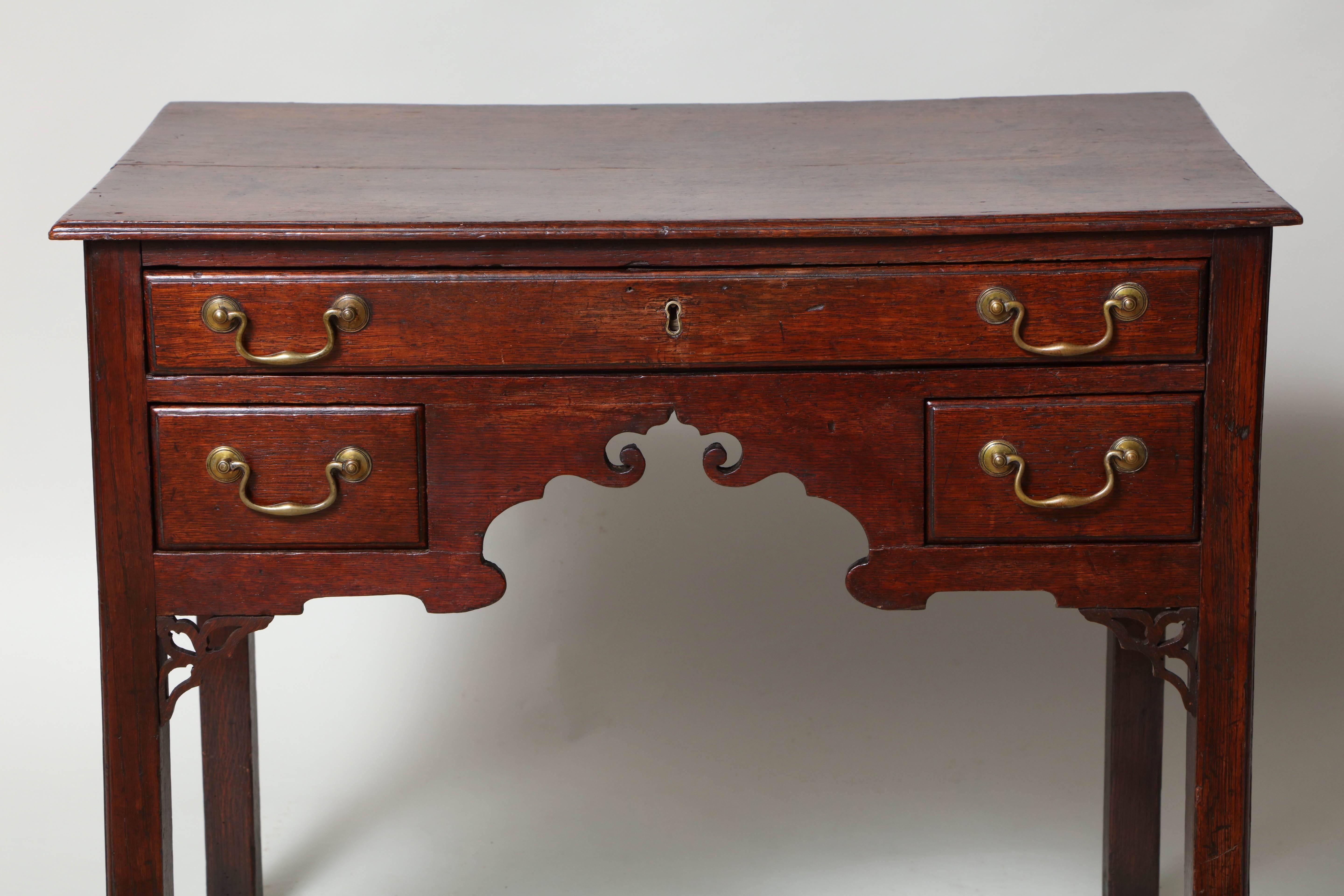 Fine 18th century Welsh oak lowboy, the book matched two plank thumb molded top over one long and two short drawers having original brass swan neck handles, the apron with richly scalloped apron, the square legs with pierced brackets, the whole with