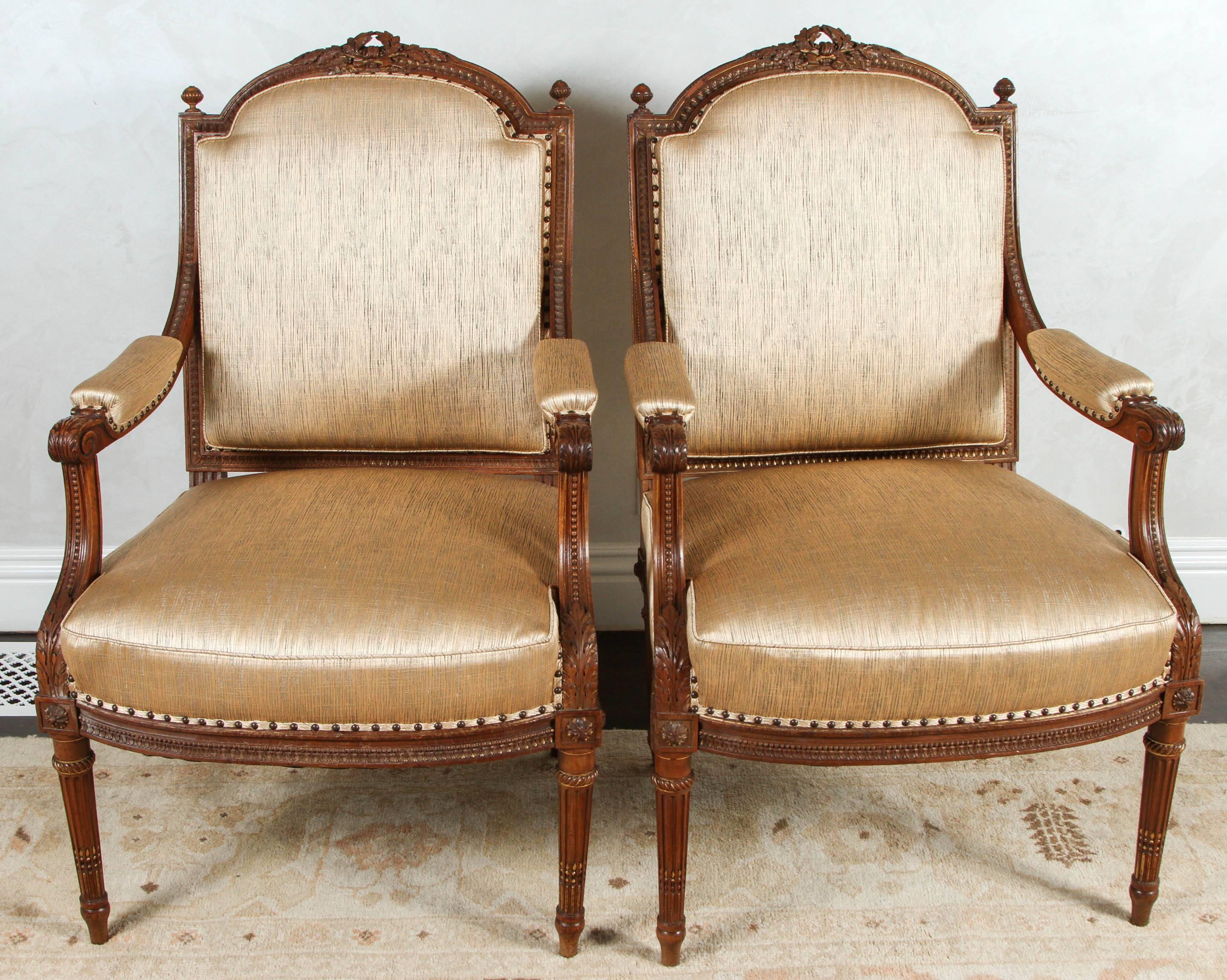 Pair of 19th century French finely carved walnut armchairs with acanthus leaf and ribbon motif. The chairs are finished with nail heads and have been newly upholstered with  silk matte gold fabric. The price in this listing is for one pair only but