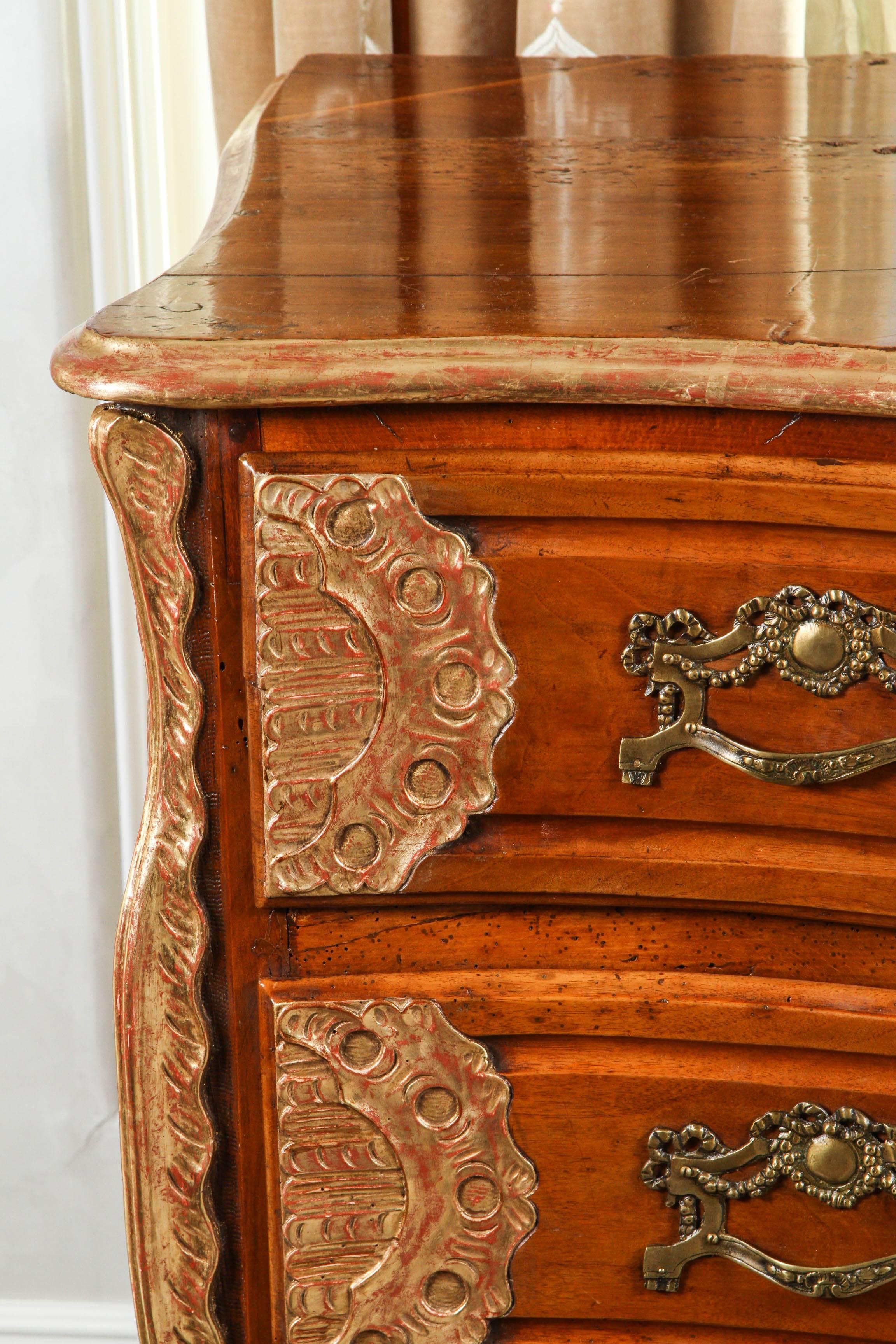 18th century Lyonaise three drawer walnut commode with carved giltwood detail and bronze drawer pulls. Both sides of this piece have two panelled side profiles. From the connoisseur collection in Los Angeles, California.
 