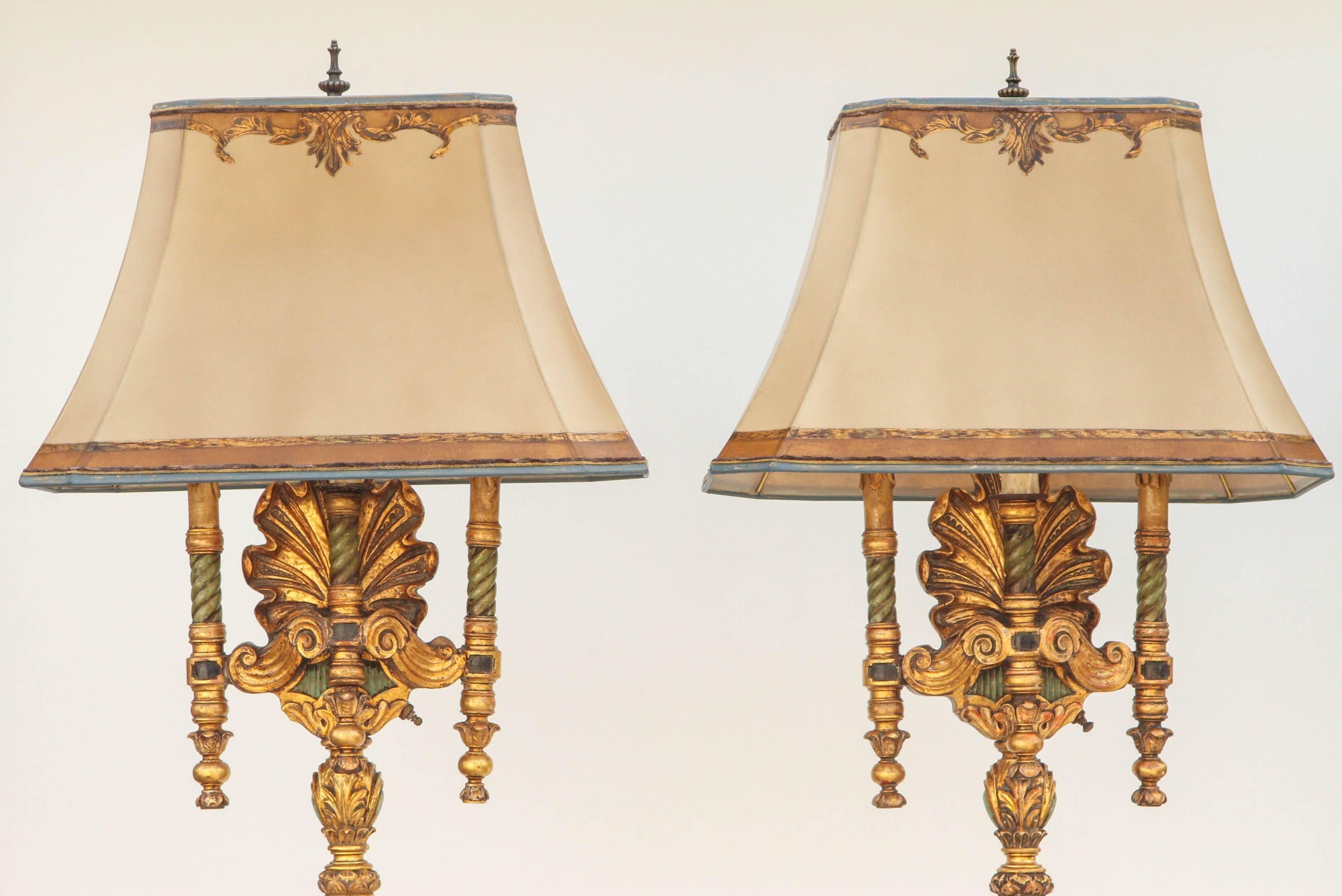 Pair of 1930s Italian carved polychrome floor lamps with a shell motif. They were originally torchieres and have been converted to floor lamps. The shades are included and are handmade of parchment paper. They are hand gilded and decorated. The