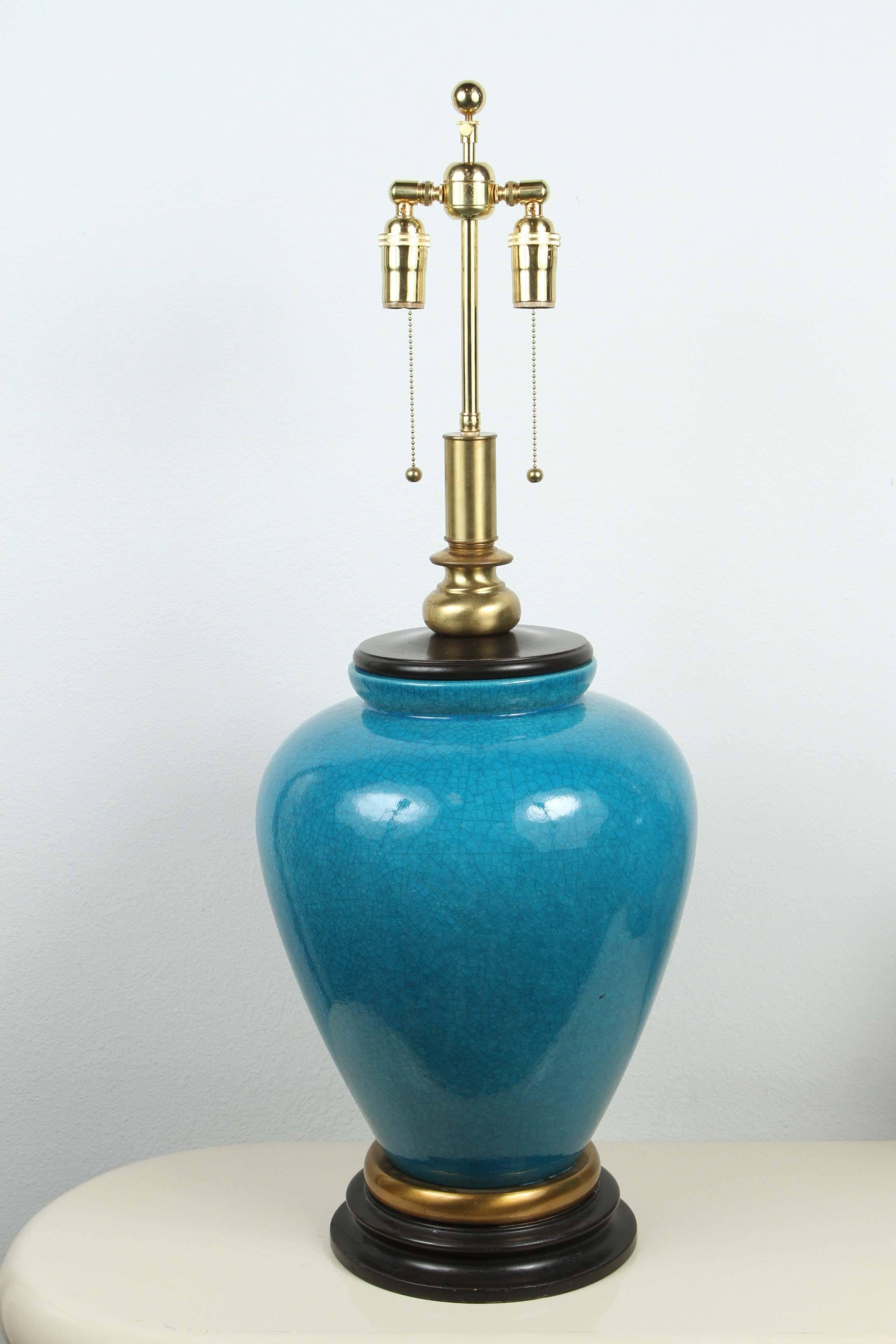 Gorgeous pair of large ceramic table lamps by Frederick Cooper. 
The lamps have a beautiful crackled glaze finishing a pure cerulean blue, which is enhanced by black and brass appointments.
The lamps have been newly rewired with brass double
