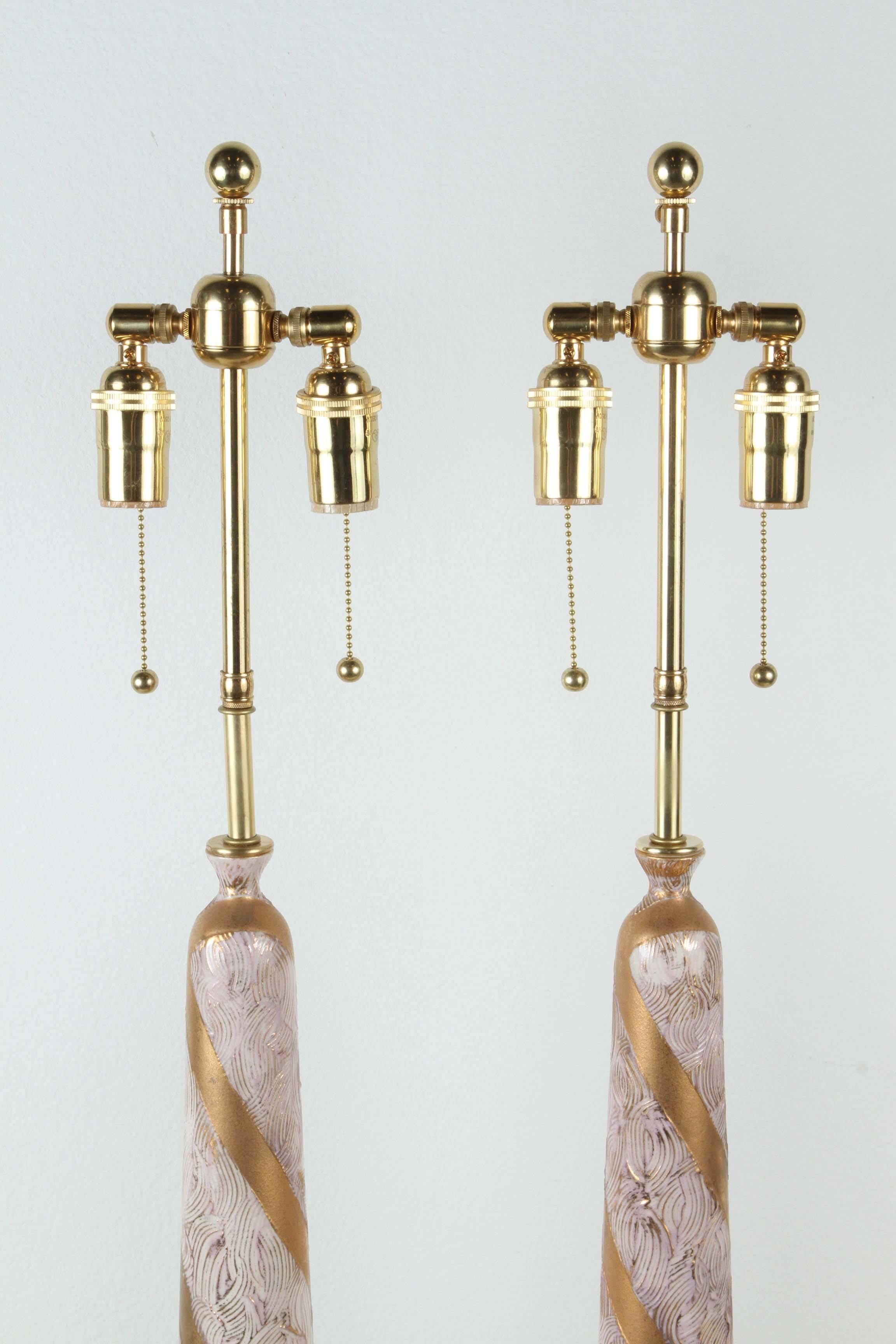 Pair of elegant ceramic table lamps.
An incised design alternates with gold glazed bands that spiral up the lamps.
The ceramic portion of the lamps are 19