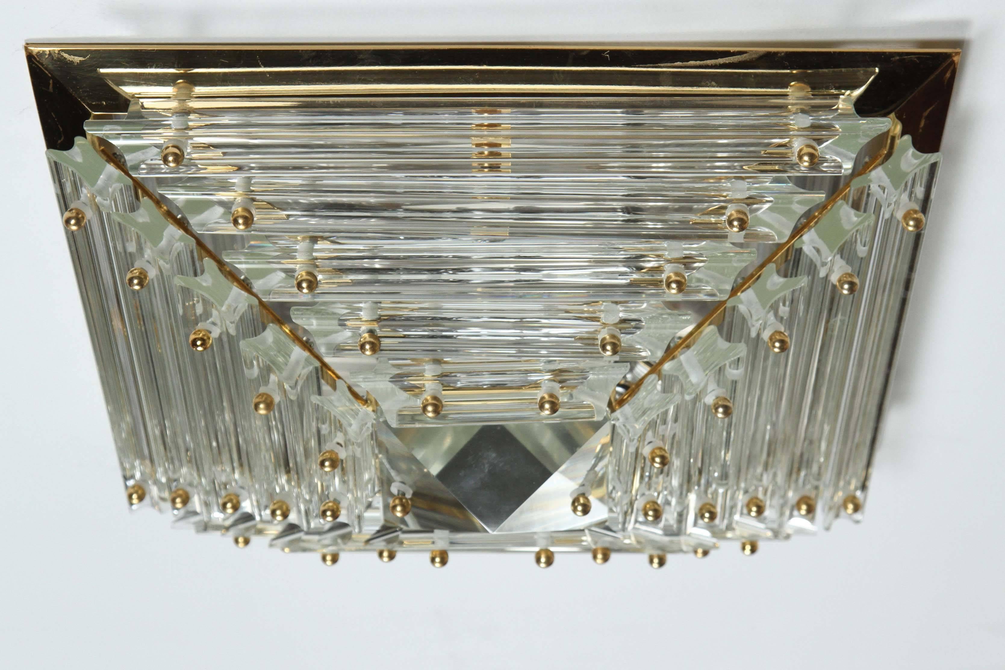 Pyramidal glass prisms flush mount fixture by Sciolari.
The glass prisms are arranged horizontally on a polished brass base to form a pyramid. They are held in place by small brass knobs. In the very center is a $