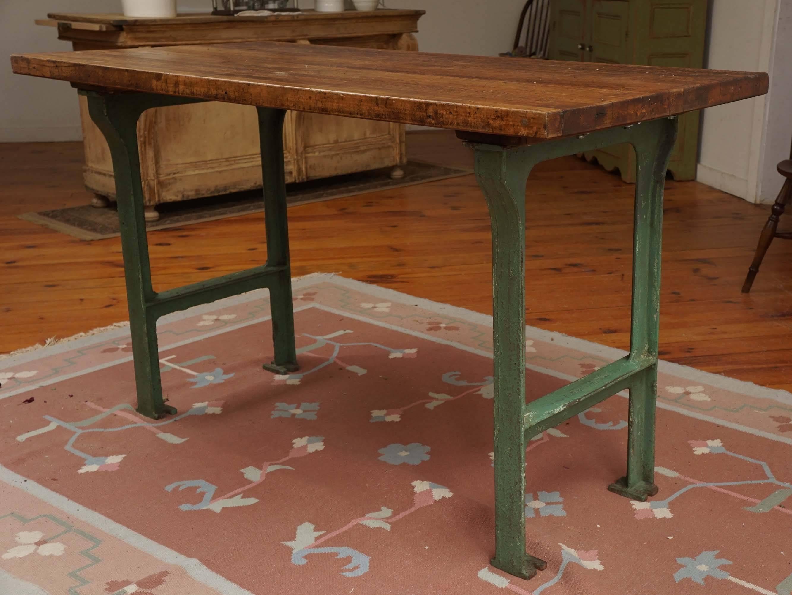 This maple top was originally a butcher block and wound up in a school in the mid west and made into a work table. This would be a perfect center island in a kitchen, with overhang on each end of the table. The base has original paint and the table