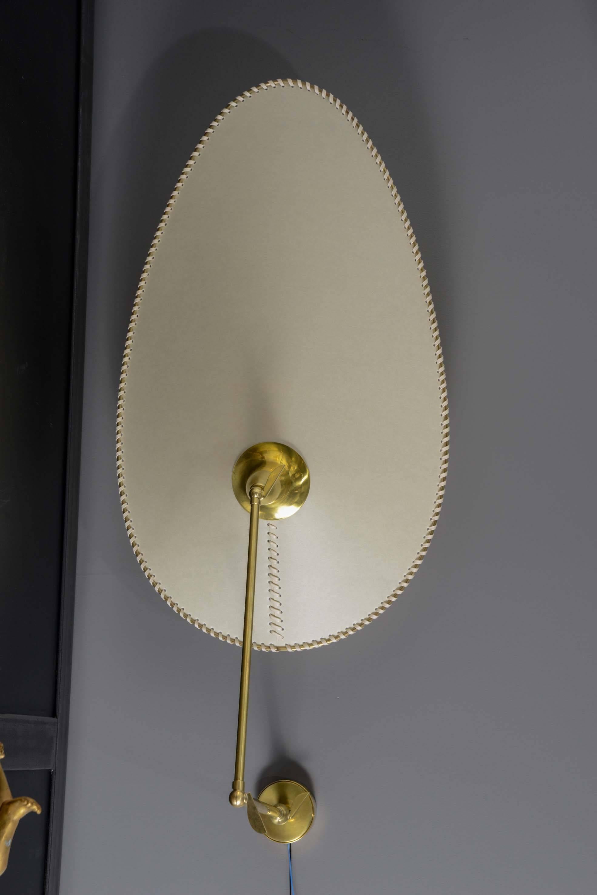 Ingenius pair of wall sconces made of a two parts articulated arm and a beautifully made, asymmetric, weaved parchment per shade.

Thanks to the three handles, the sconces can be displayed in several positions.

Each piece is signed and