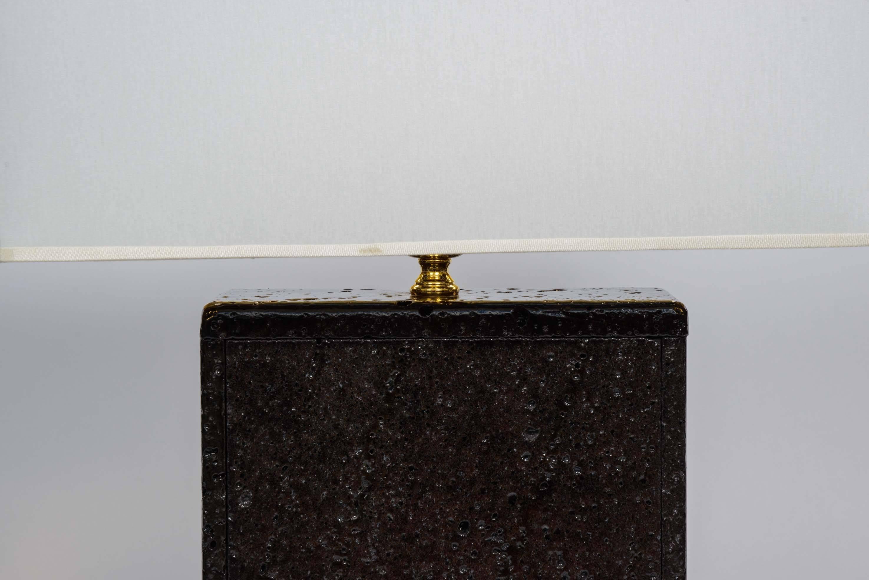 Original and unusual pair of lamps made of polished and painted lava rock, with brass setting.