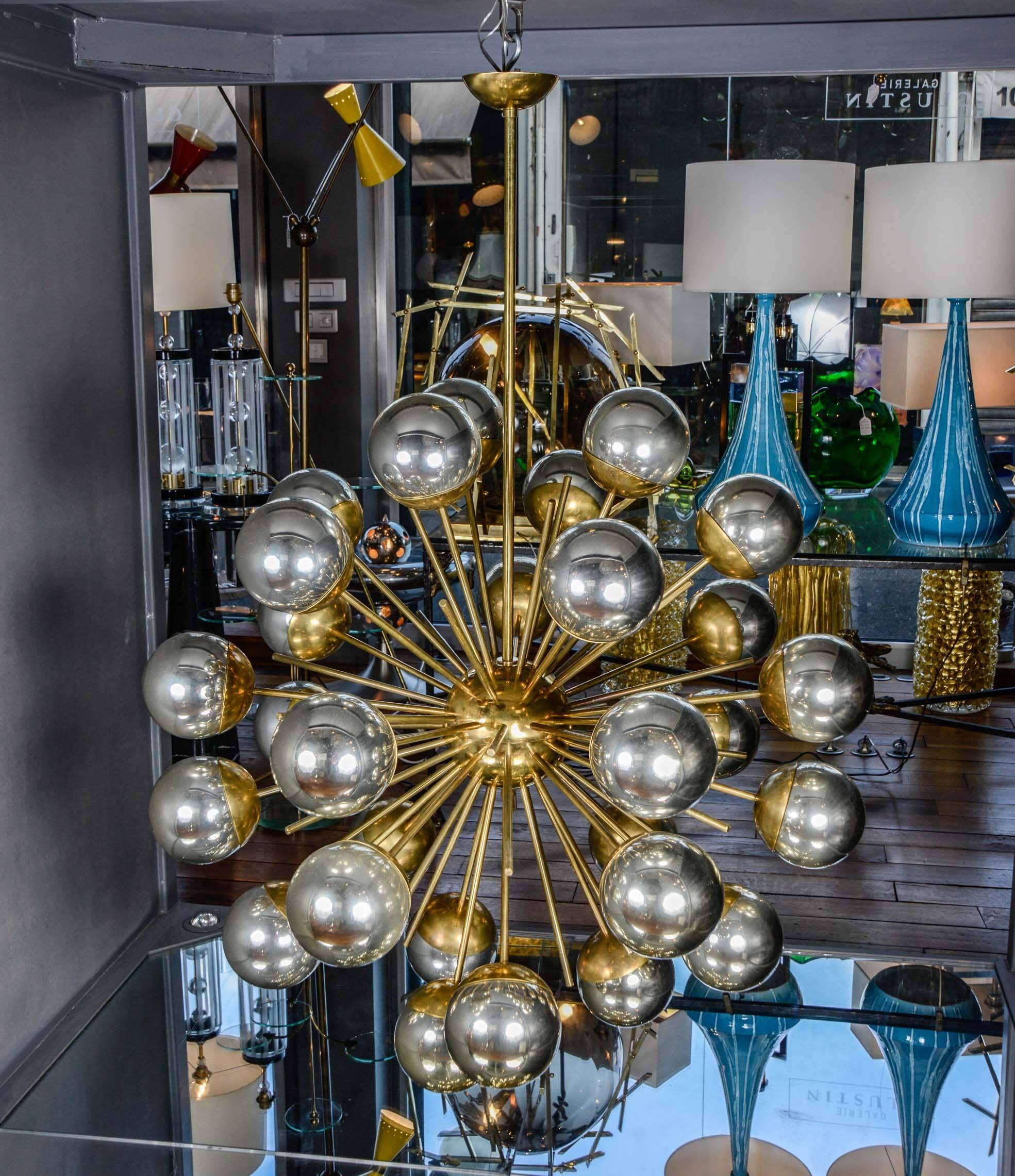 Pair of chandeliers made of brass structure with decorative rods and arms of light, each capped by a chrome-tinted, Murano glass globe.