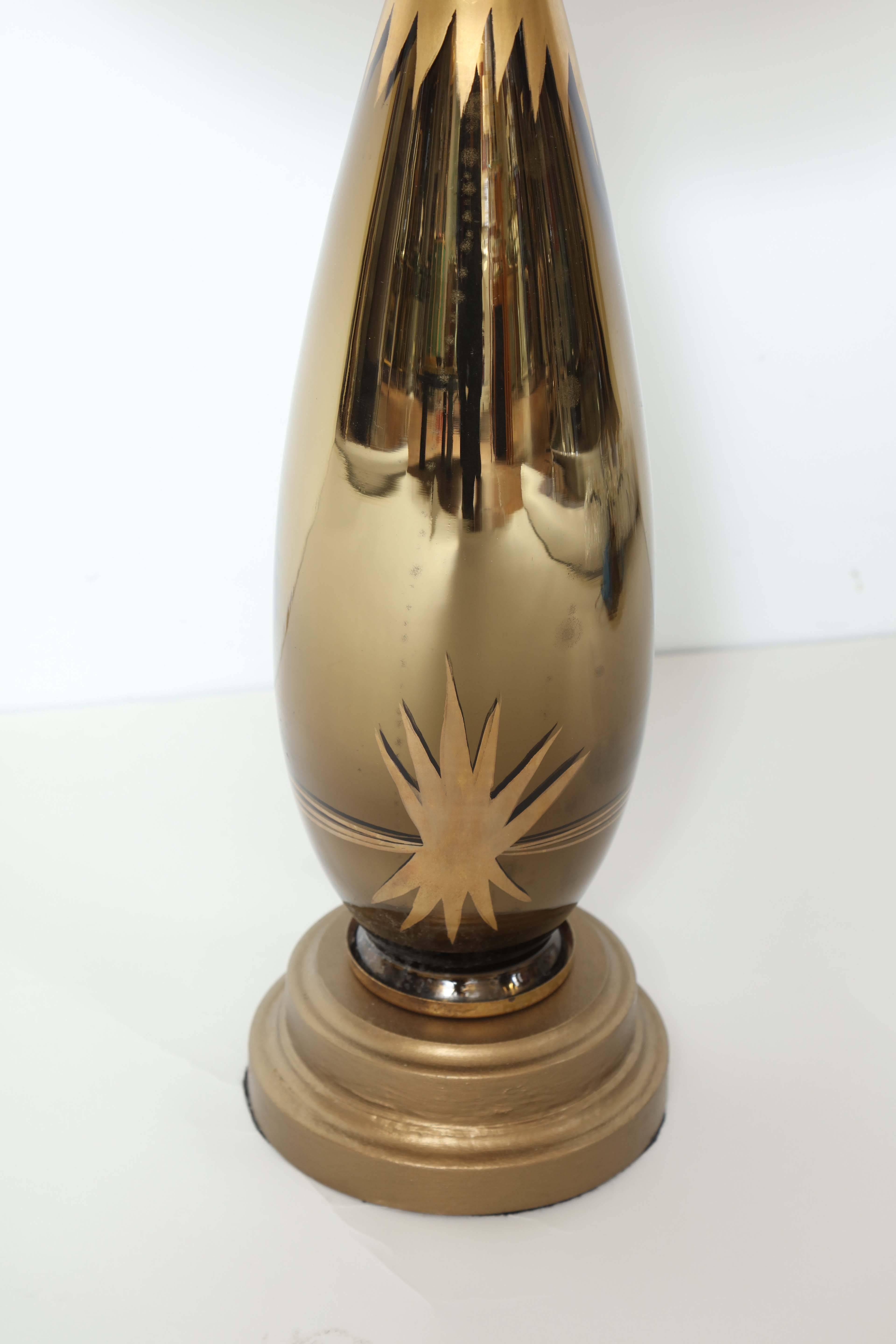 A stunning pair of Art Deco black glass lamps with gold starburst decoration and gold collar.