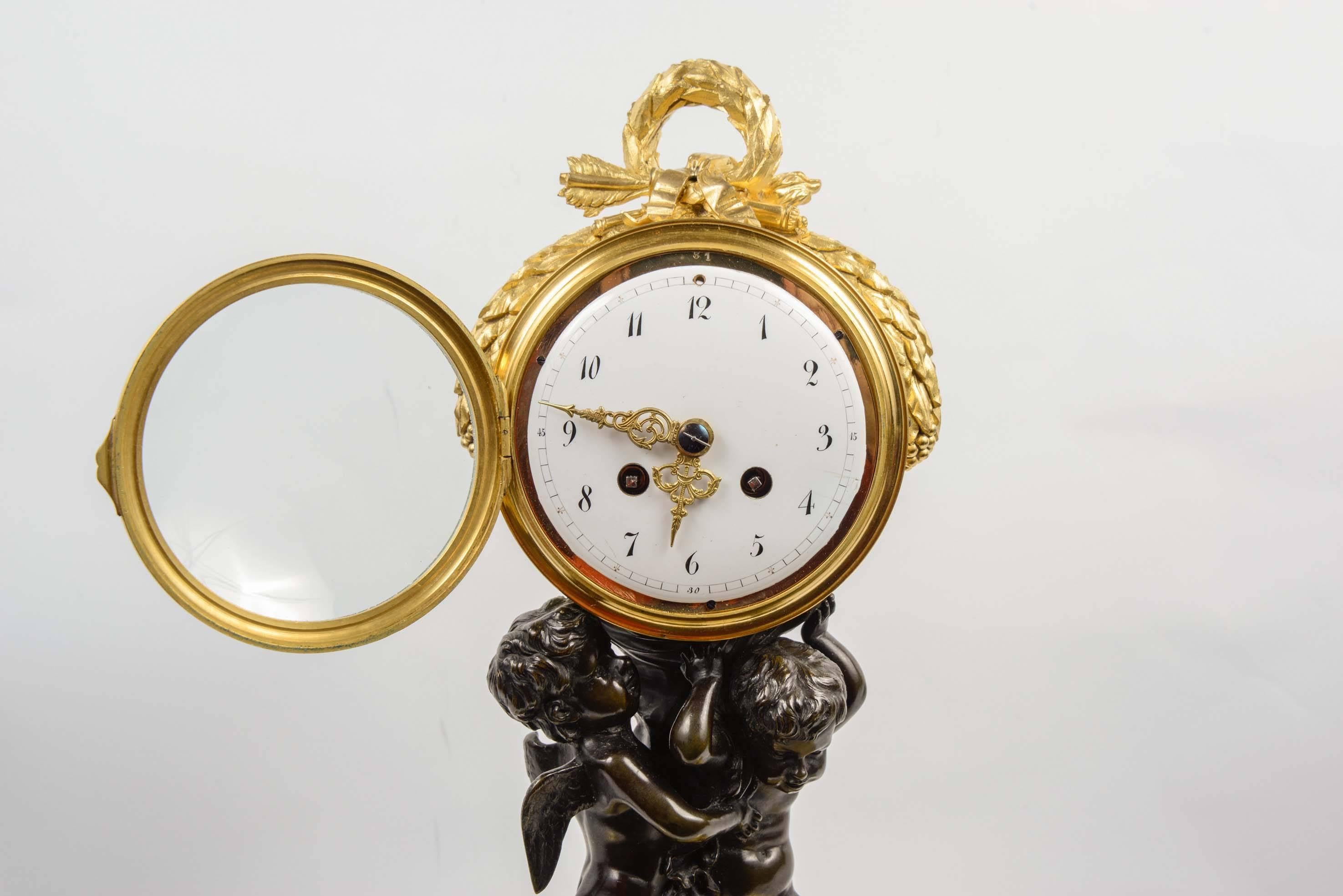 Very charming horloge in the style of Louis XVI, double patina and gilded bronze, two brown patina bronze puttis standing on a gilded bronze base, holding the movement of the clock.