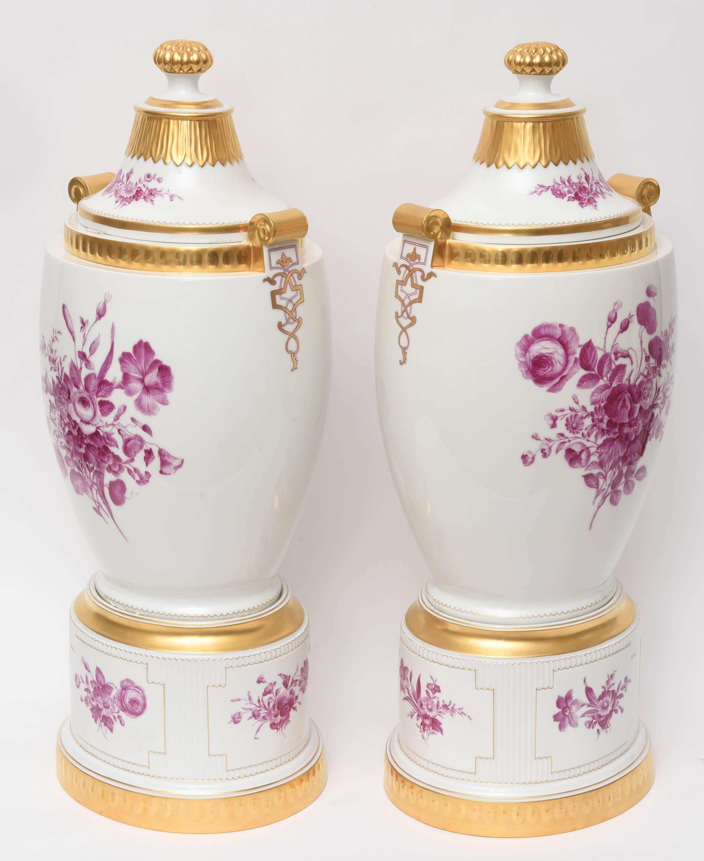 A scarce and hard to find matching pair of decorative and impressive covered urn vases in nearly pristine antique condition. Deco Era, circa 1930 and meticulously hand-painted and gilded. Detailed finials, handles and raised molding enhances these