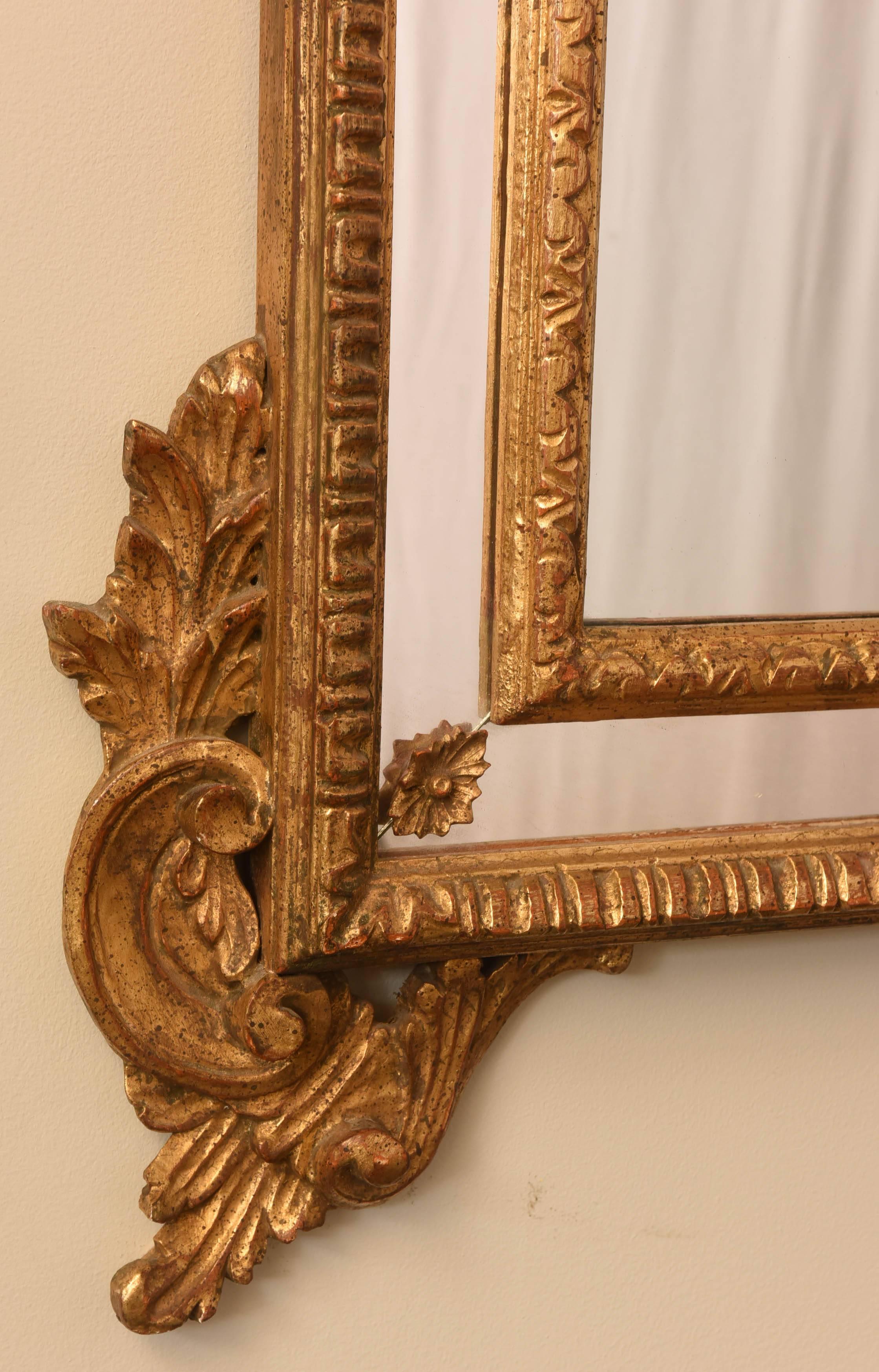 Fine mirror, having an arched form, with gadrooned edge, framed in mirrored relief, framed with elaborately carved, pierced border, scrolling floral sprays, surmounted by a pierced pediment of double C-scrolls centered by a rosette and foliate
