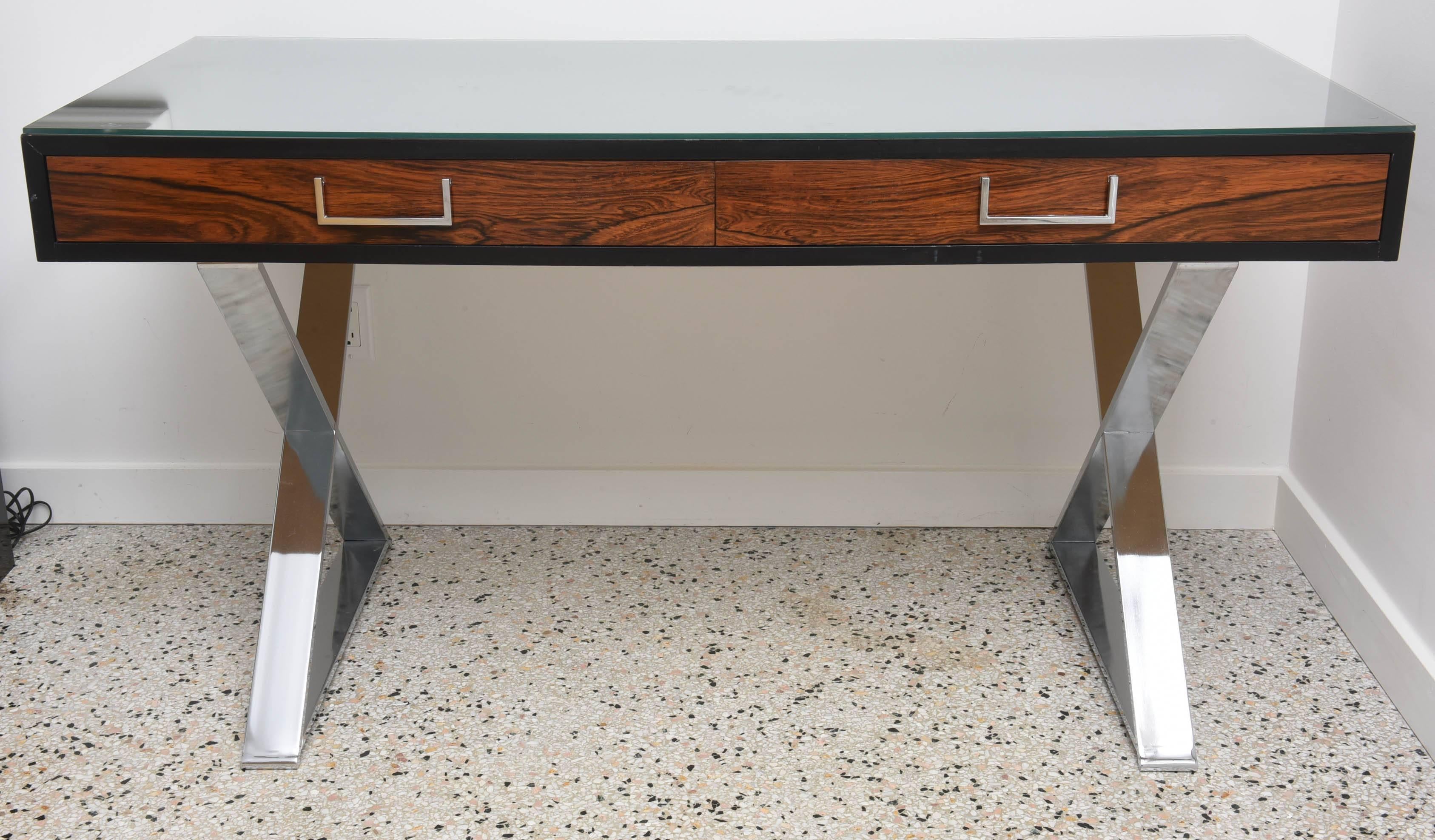 This handsome desk was designed by the iconic furniture designer Milo Baughman in the 1970s. Baughman has taken the traditional Campaign style and recreated it with modern materials and finishes.

The X-base is in polished steel and the main body
