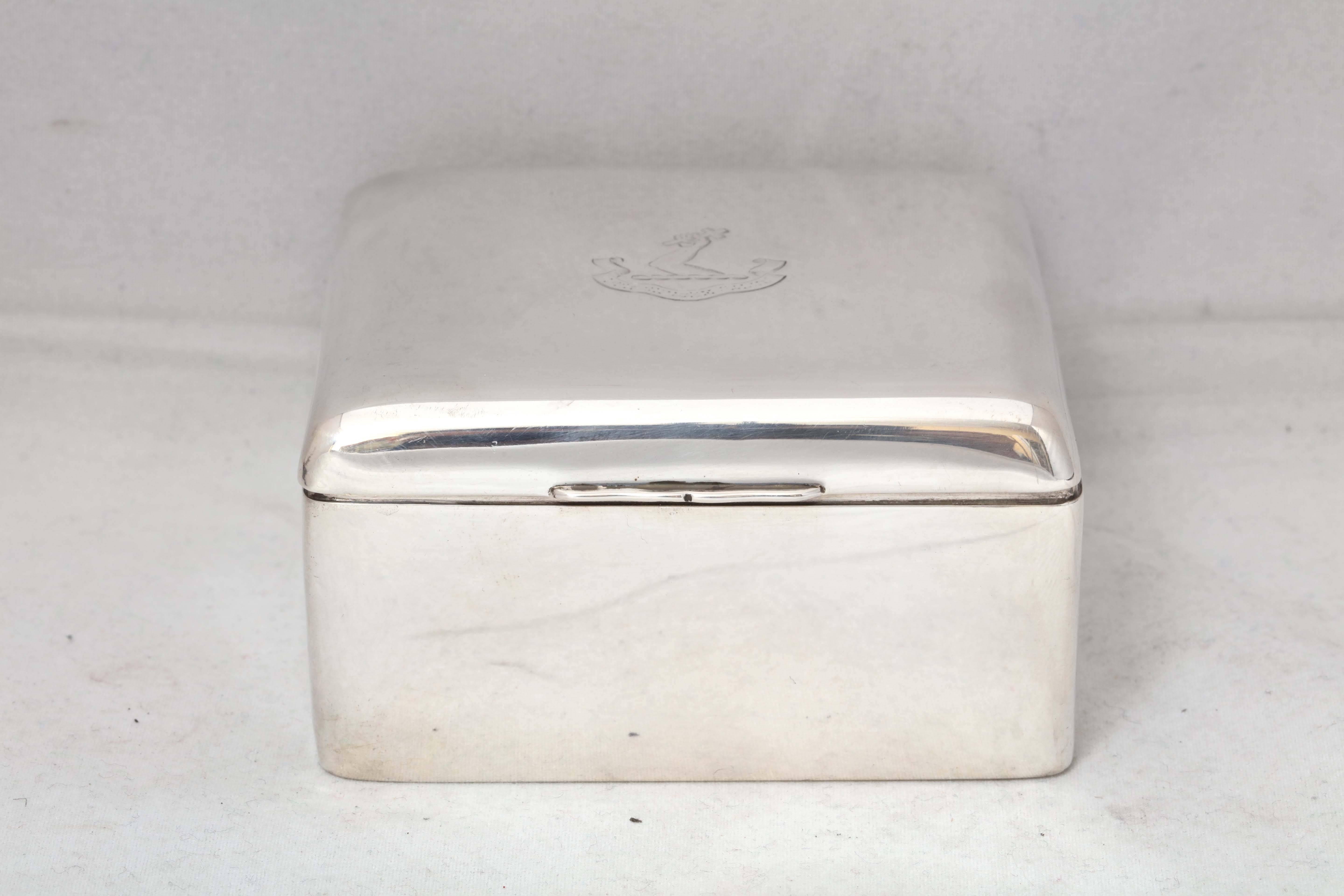 Edwardian, sterling silver table box with armorial on hinged lid, Birmingham, England, 1904. Leather underside; wood lined. Underside of lid is gilded. Hinged lid has central armorial ( a raised arm holding a cross) with motto: 