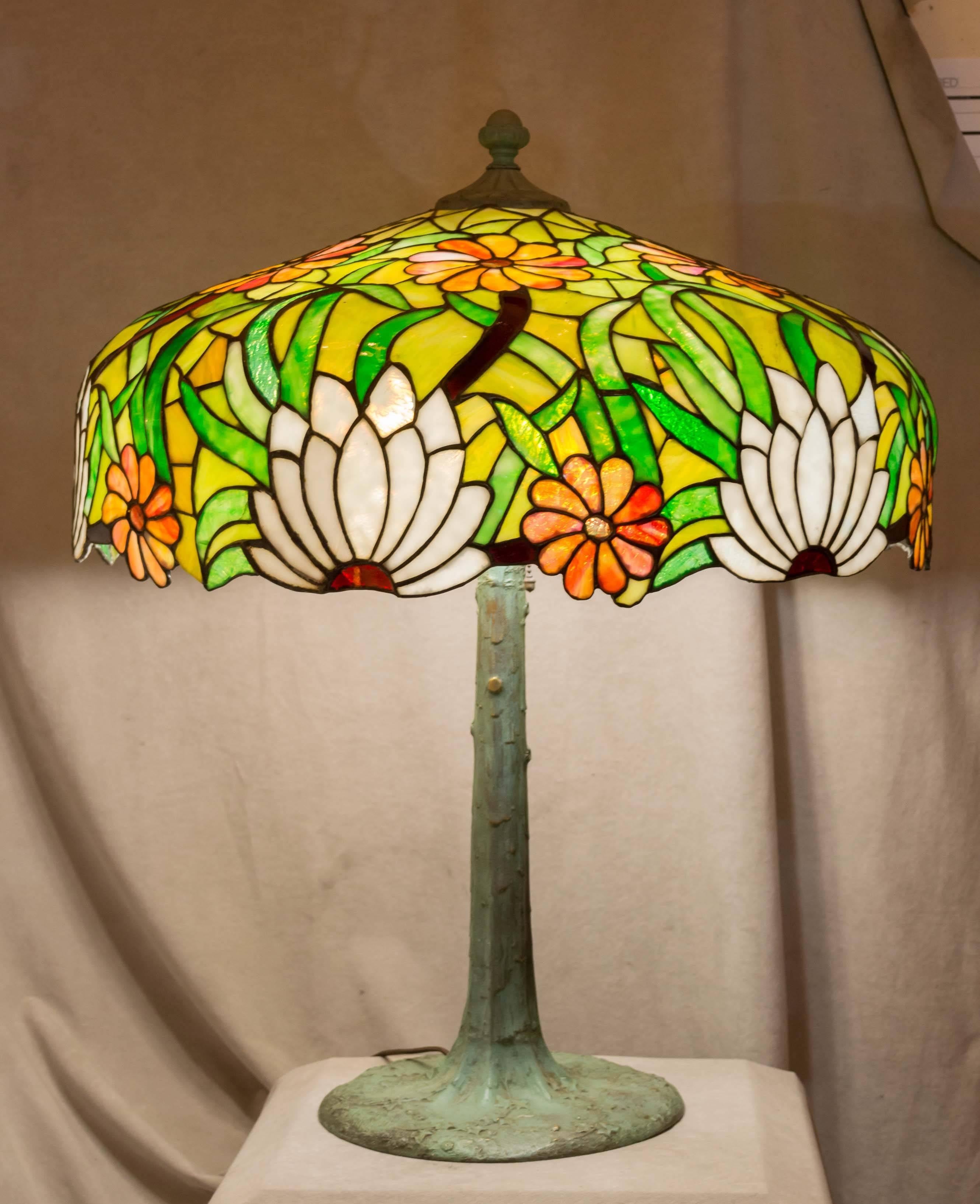 This very large and colorful table lamp is guaranteed to be a period piece of lighting. The base is bronze and has the unusual feature of five sockets. It is signed under the base plate, 