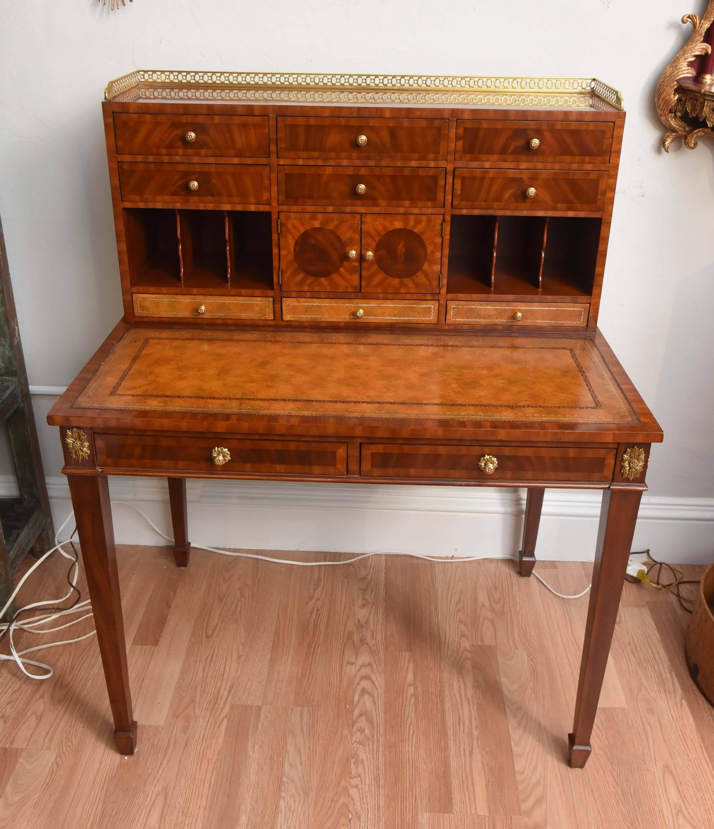 Very striking and elegant desk with upper storage compartments, tooled leather writing surfaces and side tooled leather pull outs. Finished with brass gallery on top.