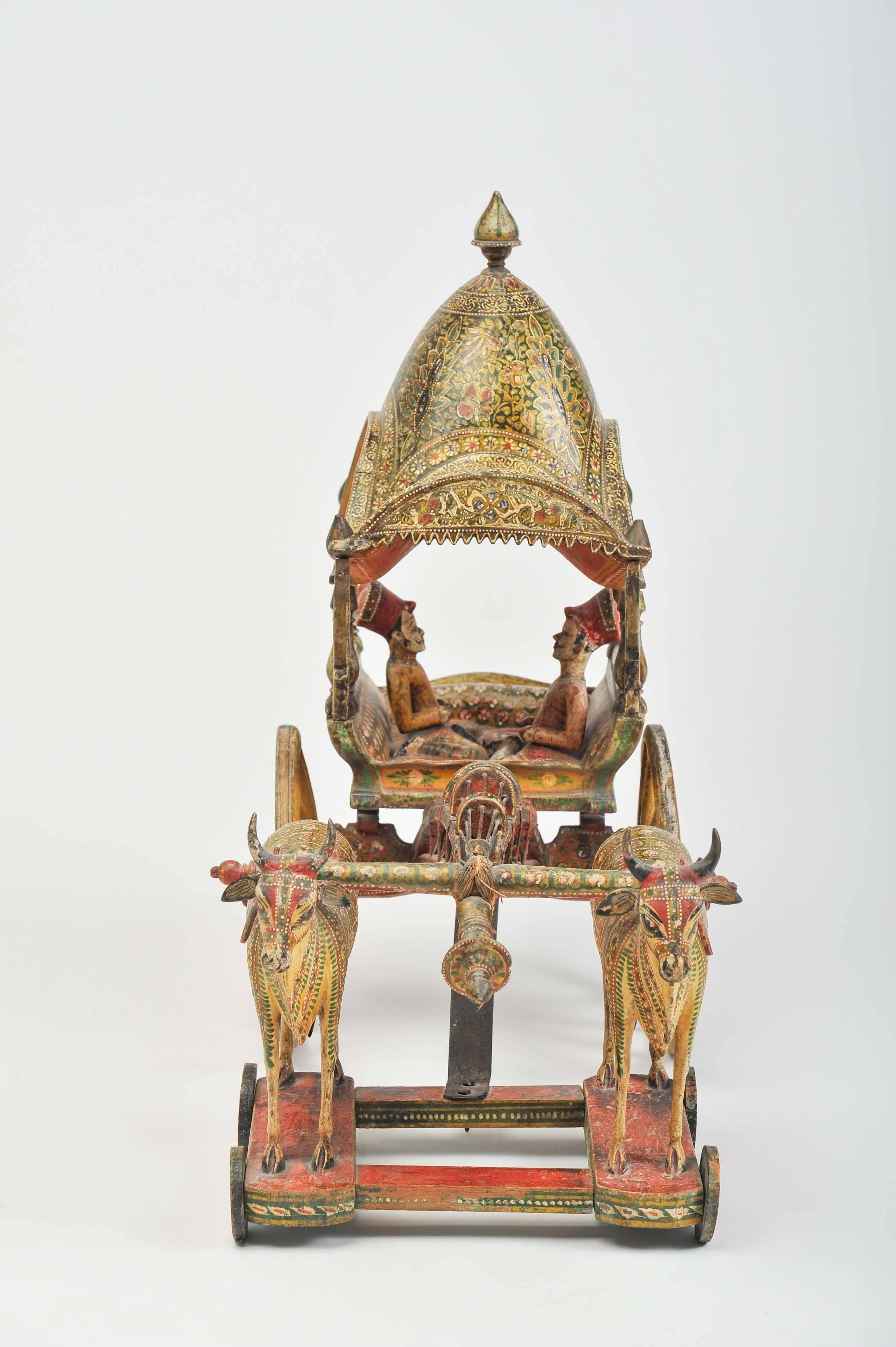 An elaborate and superbly detailed early 20th century Kashmiri model of an Ox and cart realistically modelled with two turbaned men sitting crossed-legged in the carriage drawn by two oxen, the carriage and beam with chiselled boteh and overall